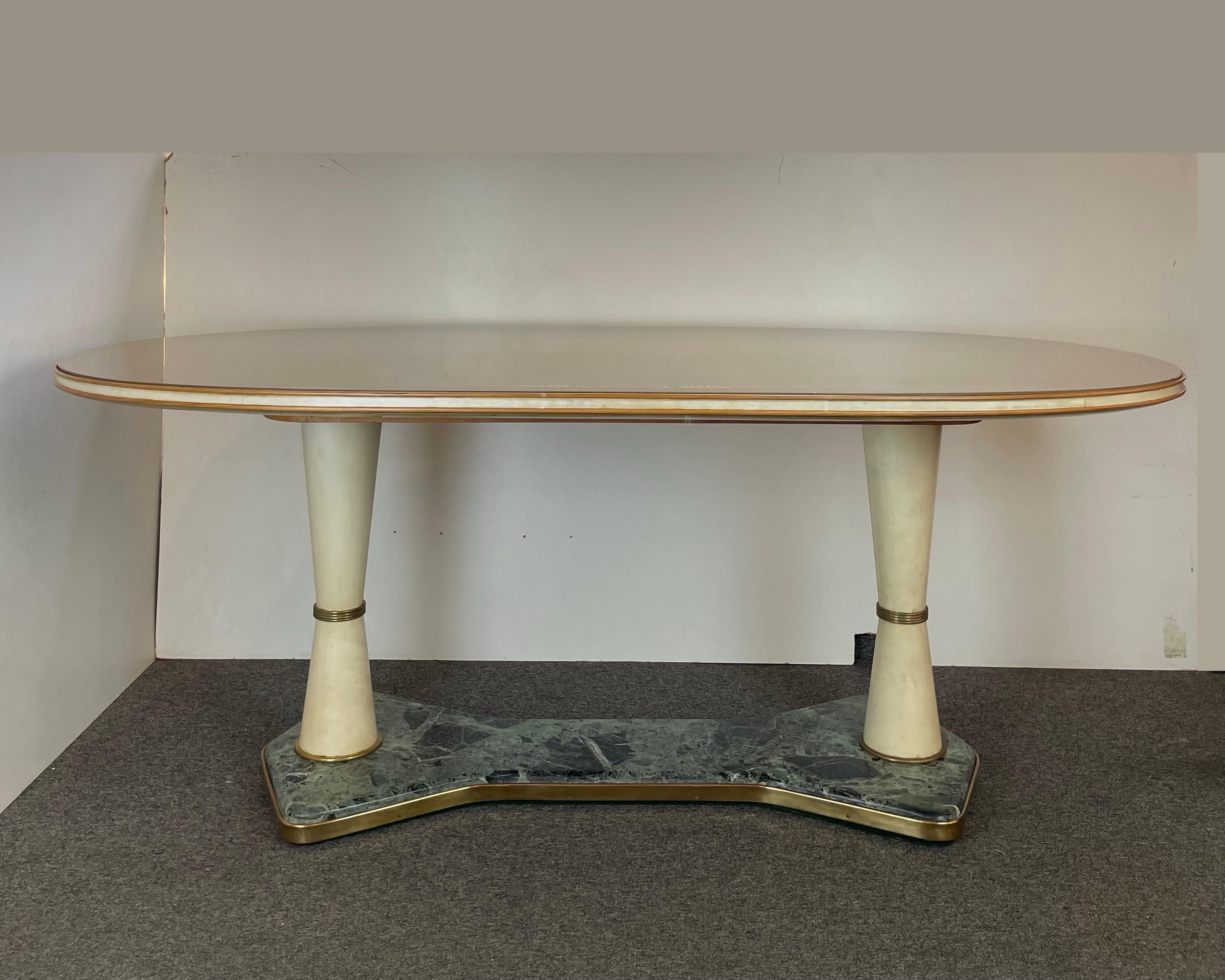 Stupefacente tavolo da pranzo o centro tavola degli anni '40 realizzato con materiali rari ed eclettici come marmo verde delle Alpi, pergamena, ottone, legno e vetro dipinto con fregio in foglia d'oro. Attribuito all'atelier italiano La Permanente