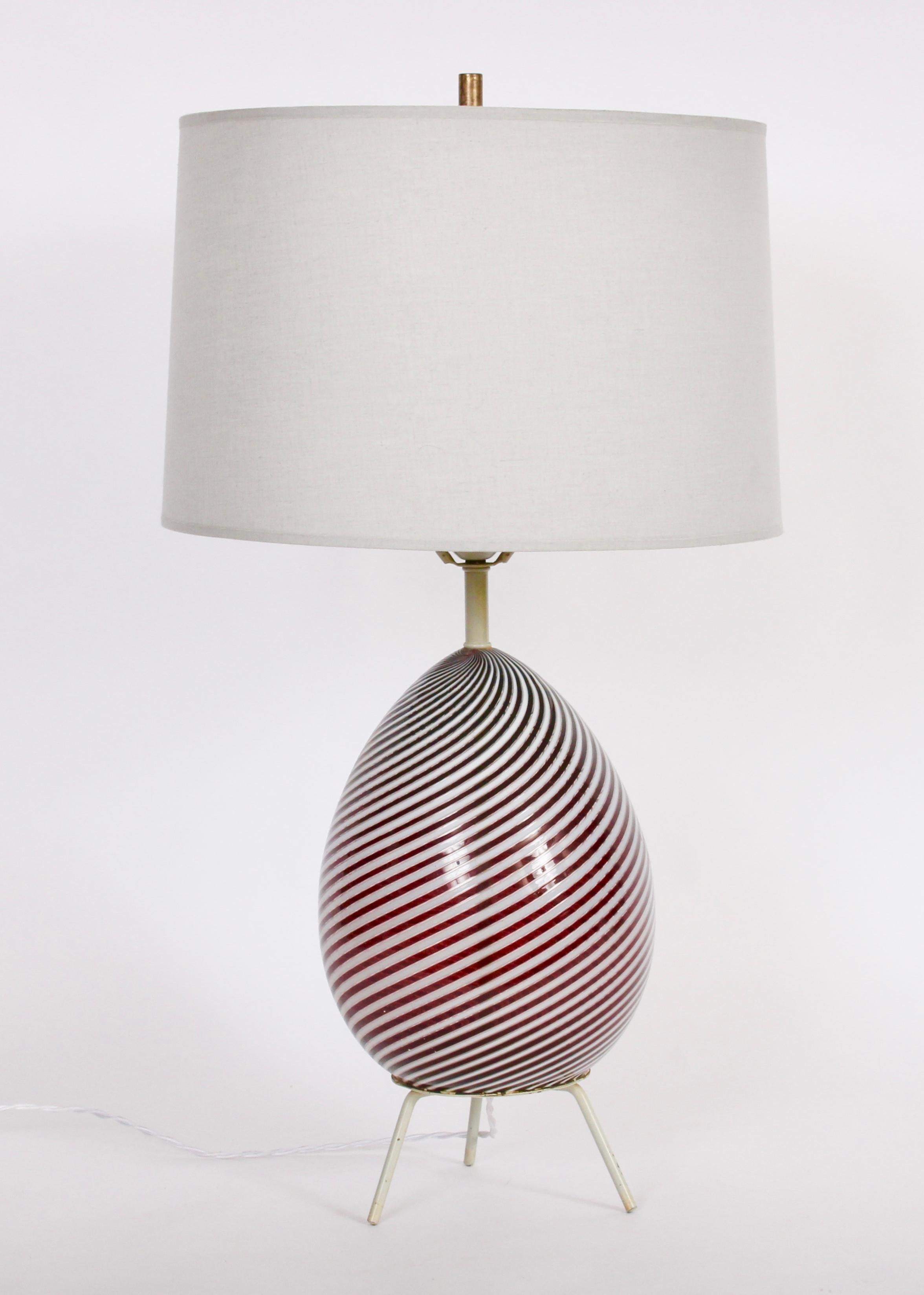 Dino Martens for Aureliano Toso deep cranberry and opaque white swirl Murano Glass Table Lamp, 1960s.  Featuring a handcrafted egg form in translucent glass with parallel diagonal stripes in cranberry and white with original Taupe enameled hardware