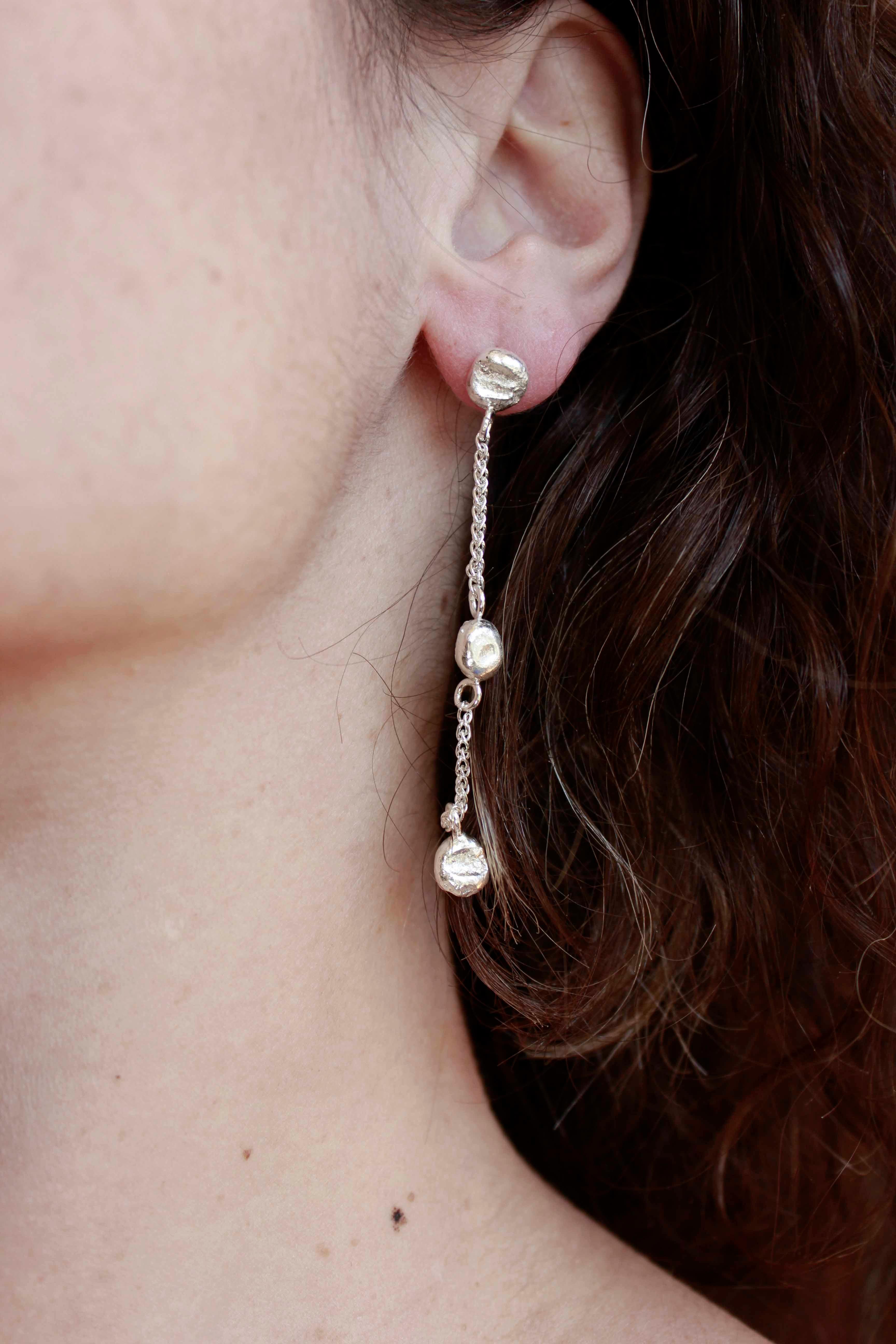 Simple and elegant, the Dione Earrings consist of three silver balls each, combined with silver chain.

Each earring has approximately 6.5cm length.

The small organic balls are made from our silver scrap, which means they are 100% recycled and