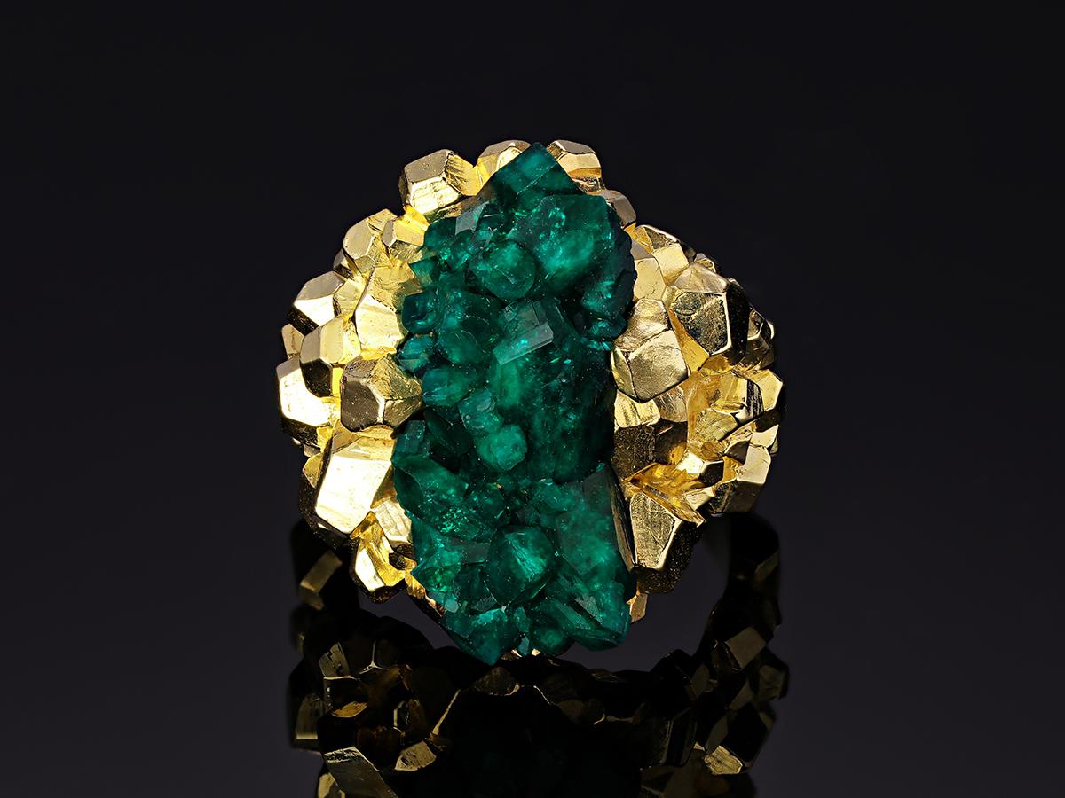 This incredible one of a kind ring showcases the natural beauty of the dioptase crystal, displaying it like a treasure-trove bursting with intense color in the center. Mined from Kazakhstan, this fine quality dioptase exhibits an intense