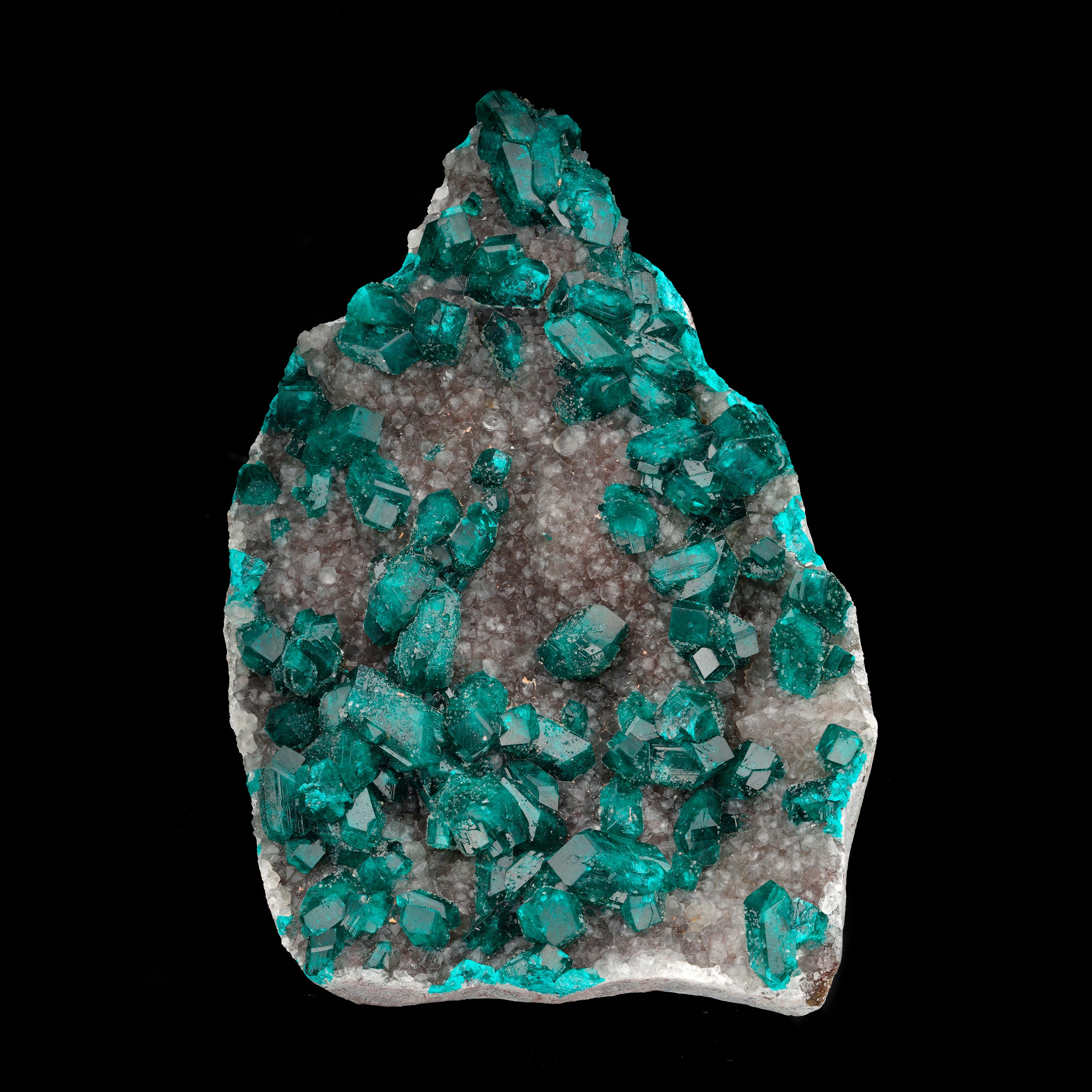 This sparkling specimen from the DRC features moderately sized, deep emerald green, fully formed and gemmy dioptase crystals growing on a thick bed of lustrous calcite crystals for a unique and aesthetic combination piece perfect for