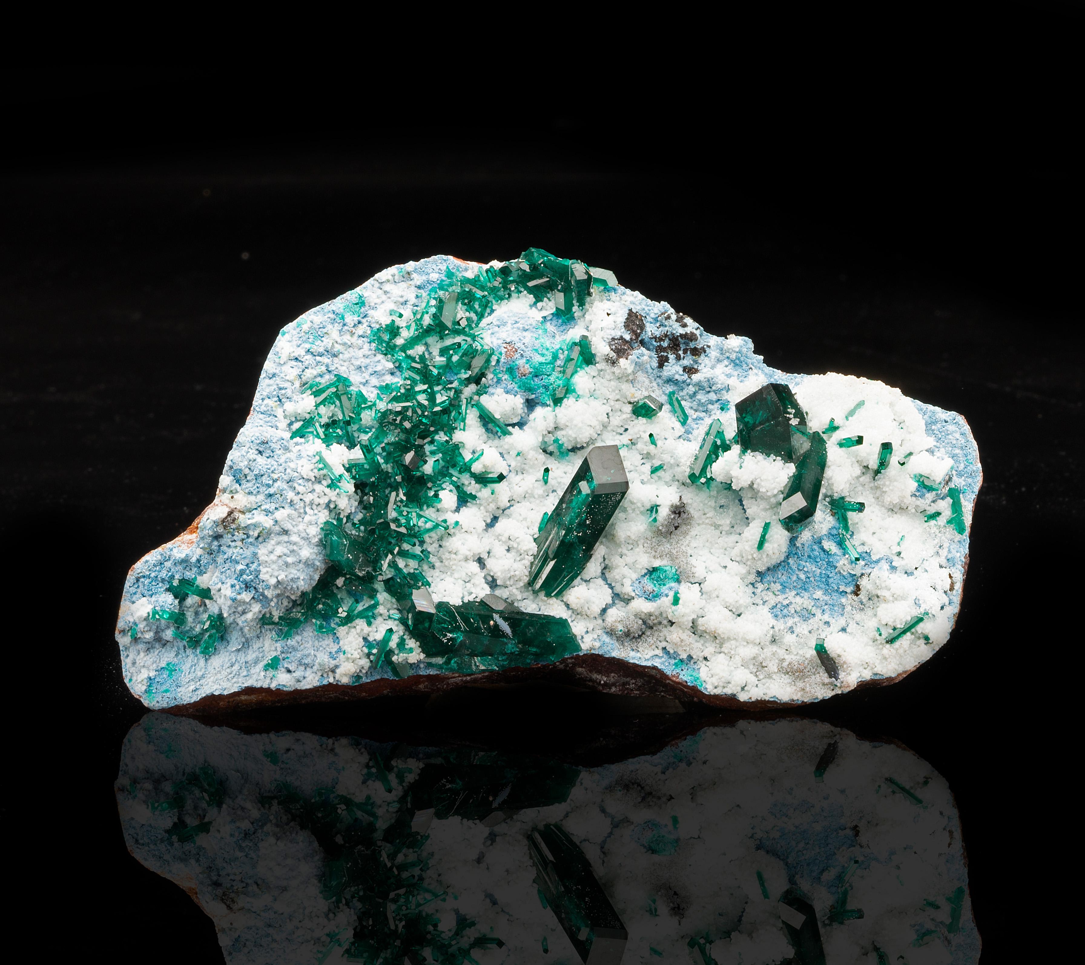 This landscape of the sky blue copper silicate mineral plancheite features generously sized, lustrous and deeply pigmented dioptase crystals emerging from mounds of sparkling, snowy calcite. The dioptase displays the mineral's characteristic clarity
