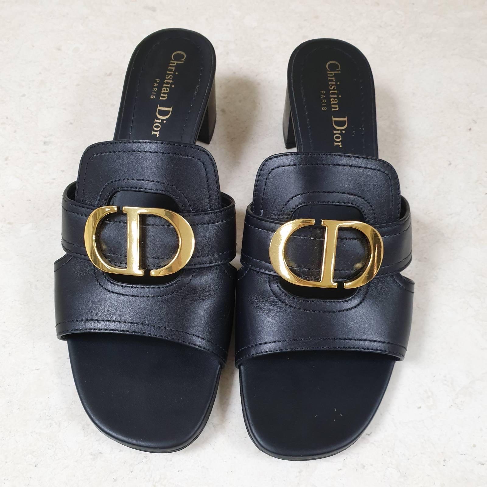 

Stemming from the 30 Montaigne collection, the black leather slide is a key piece for an effortless style. Its upper is adorned with a gold 'CD' accessory, highlighting the beautiful leather work and emblematic quality of the shoe. The mule is set