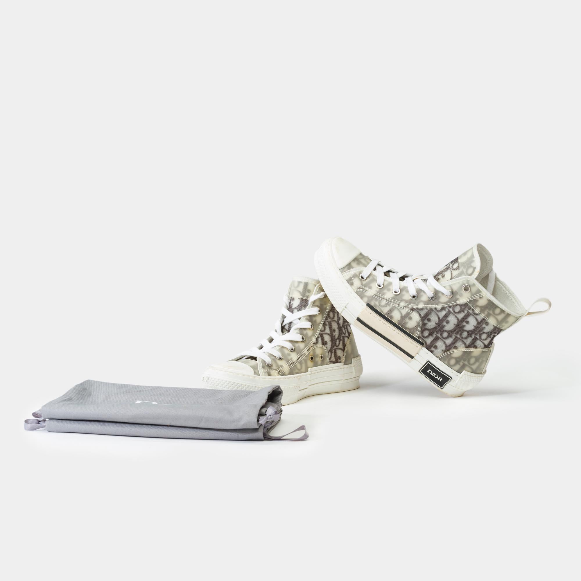 The​ ​B23​ ​high-top​ ​sneaker​ ​stands​ ​out​ ​with​ ​its​ ​overlay​ ​of​ ​transparent​ ​panels​ ​and​ ​black​ ​and​ ​white​ ​Dior​ ​Oblique​ ​canvas.​ ​This​ ​model​ ​incorporates​ ​the​ ​timeless​ ​codes​ ​of​ ​classic​ ​high-top​ ​sneakers,​