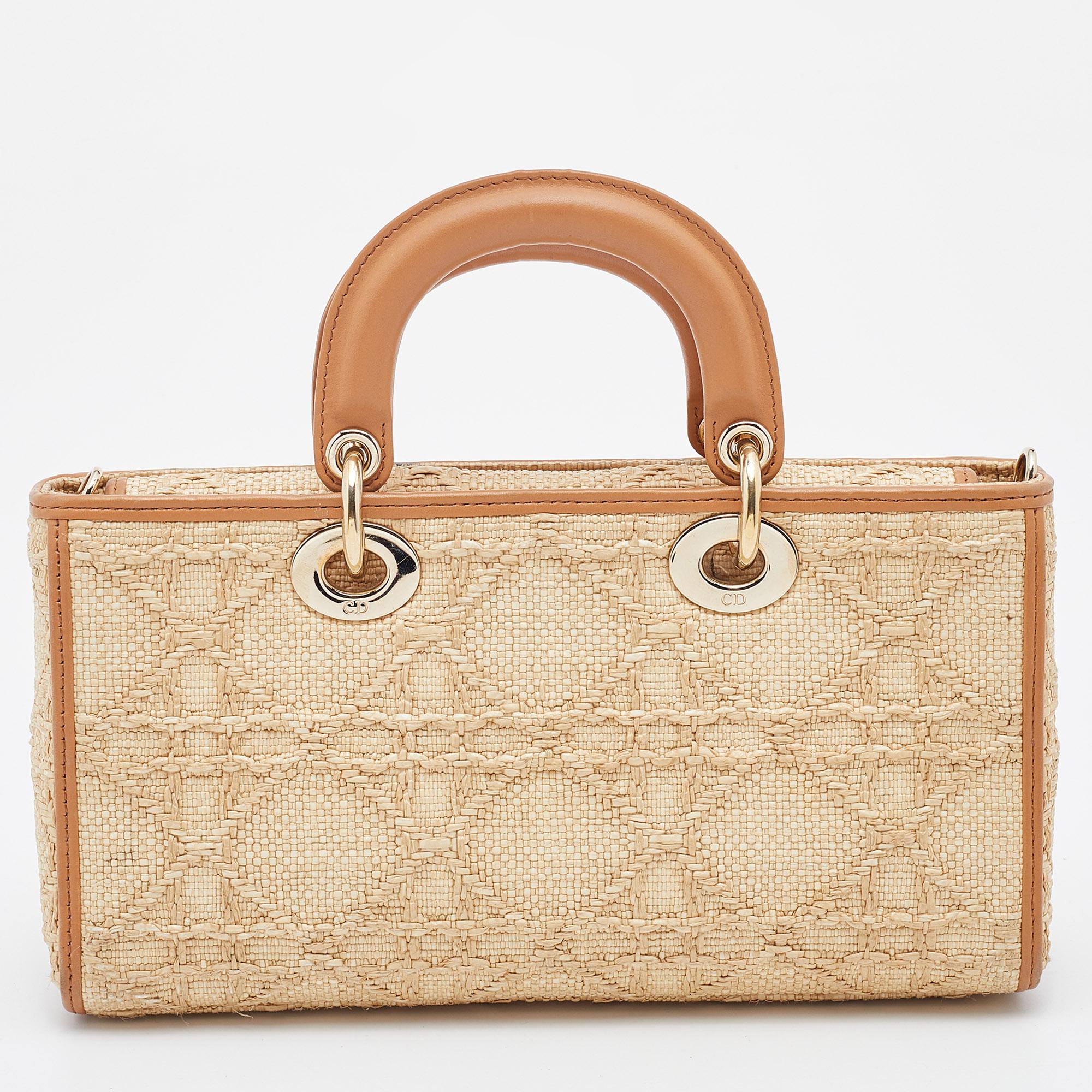 Get style and carry your essentials with ease using this Lady D-Joy bag by Dior. It has been crafted from raffia employing the signature Cannage motif, and is enhanced with leather trims & gold-tone hardware. The bag has two handles and a strap.


