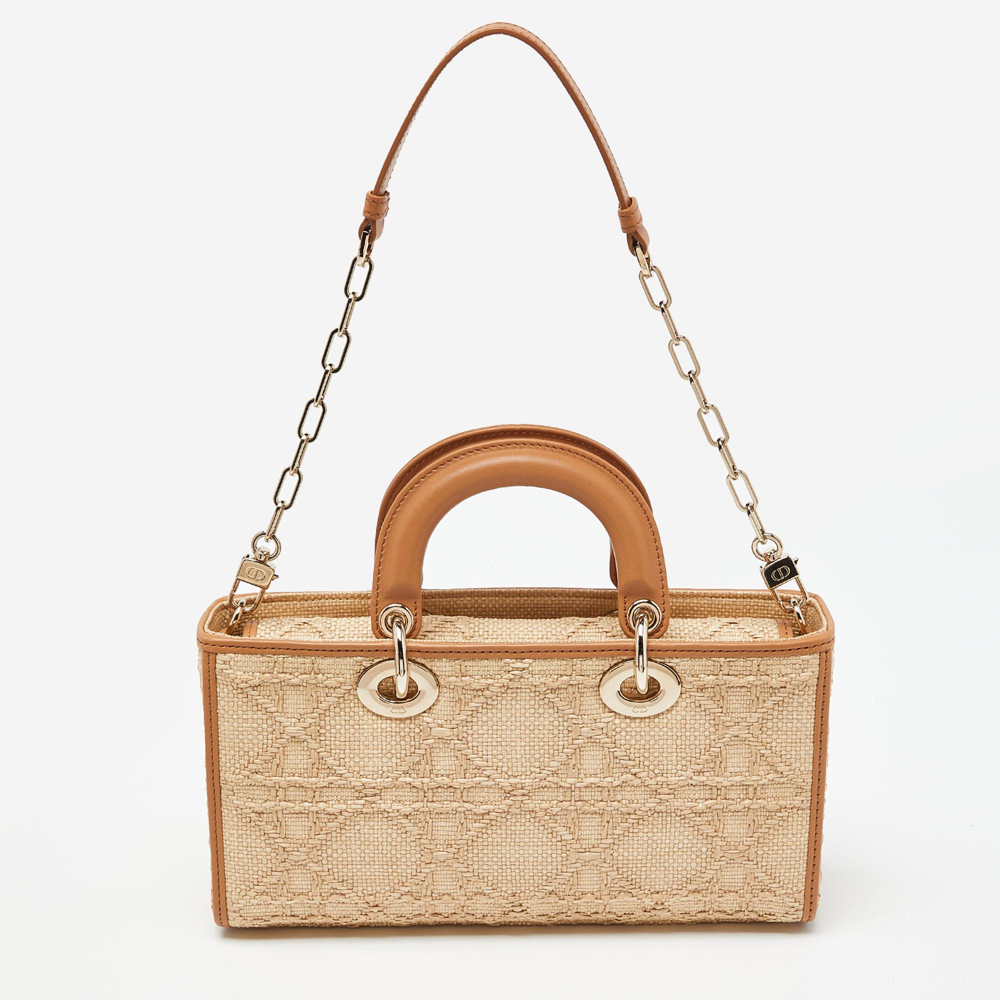 Get style and carry your essentials with ease using this Lady D-Joy bag by Dior. It has been crafted from raffia employing the signature Cannage motif, and is enhanced with leather trims & gold-tone hardware. The bag has two handles and a