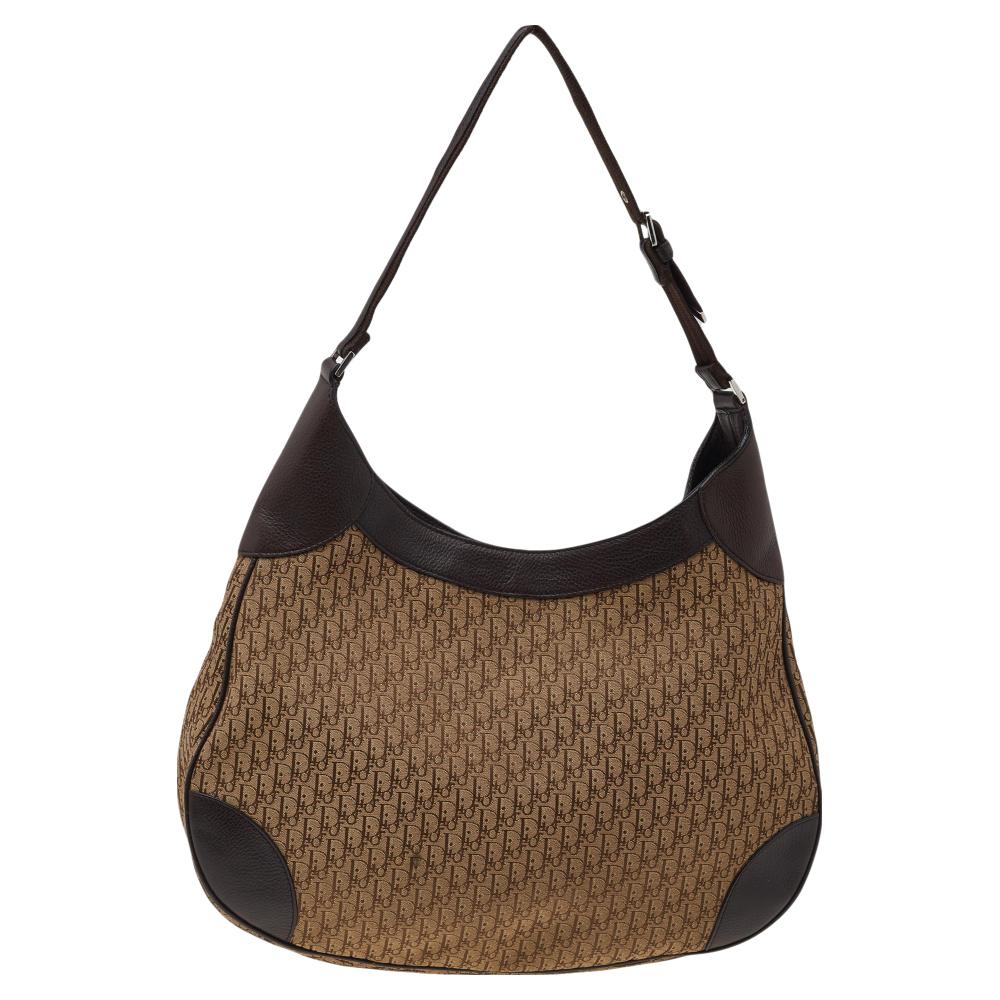 Modernize your wardrobe by adding this hobo to your collection. This creation from the House of Dior is absolutely gorgeous. Made with signature canvas and leather, this beige & brown hobo incorporates signature beauty. To add to its features, a