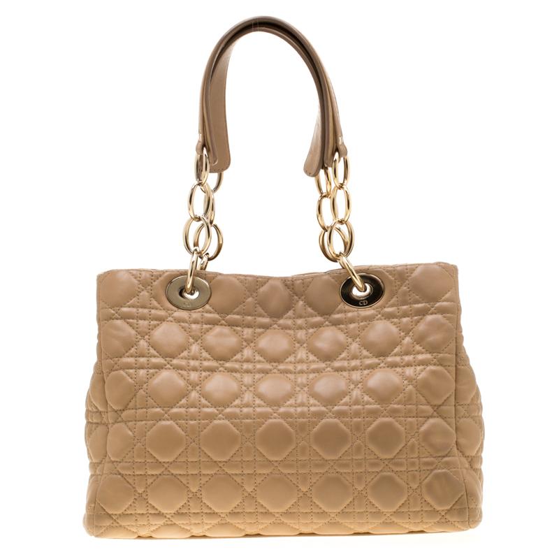 This stylish accessory is exceptionally designed by the fashion house of Christian Dior. Crafted from beige leather, this beauty represents the signature cannage quilt. Adorned with brand lettering at the front, it comes with two top handles and