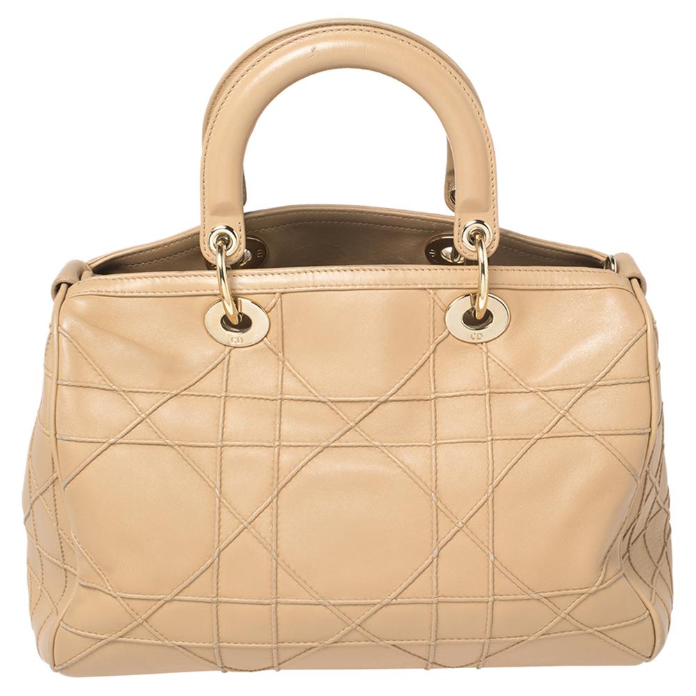 This Granville Polochon from Dior is a bag that every fashionista craves to possess. The bag has been crafted from leather and it carries a sleek beige exterior. It is equipped with a nylon interior, two rolled handles with a detachable shoulder