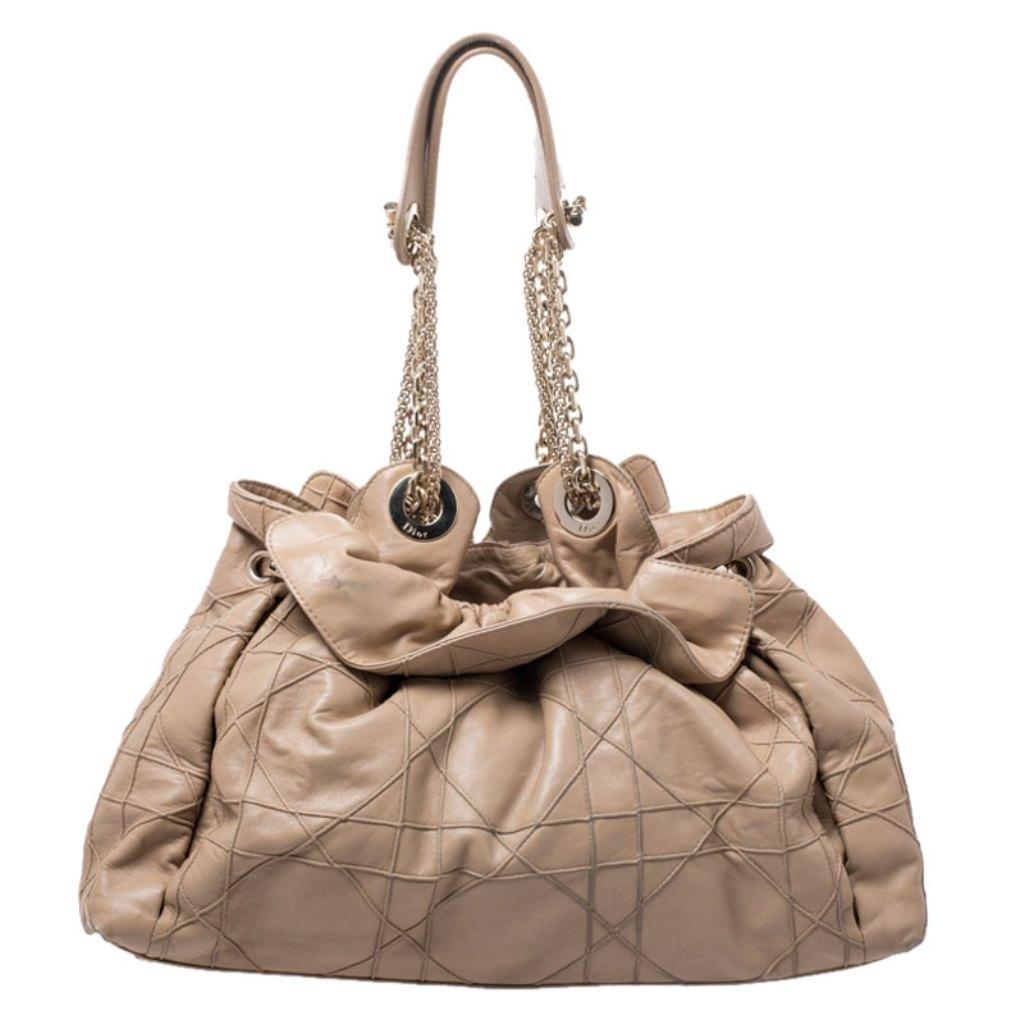 This stylish Le Trente hobo from Dior has been crafted from beige leather and styled with their signature cannage pattern. The bag features dual chain straps with leather shoulder rest, a CD cutout charm, a drawstring closure and protective metal