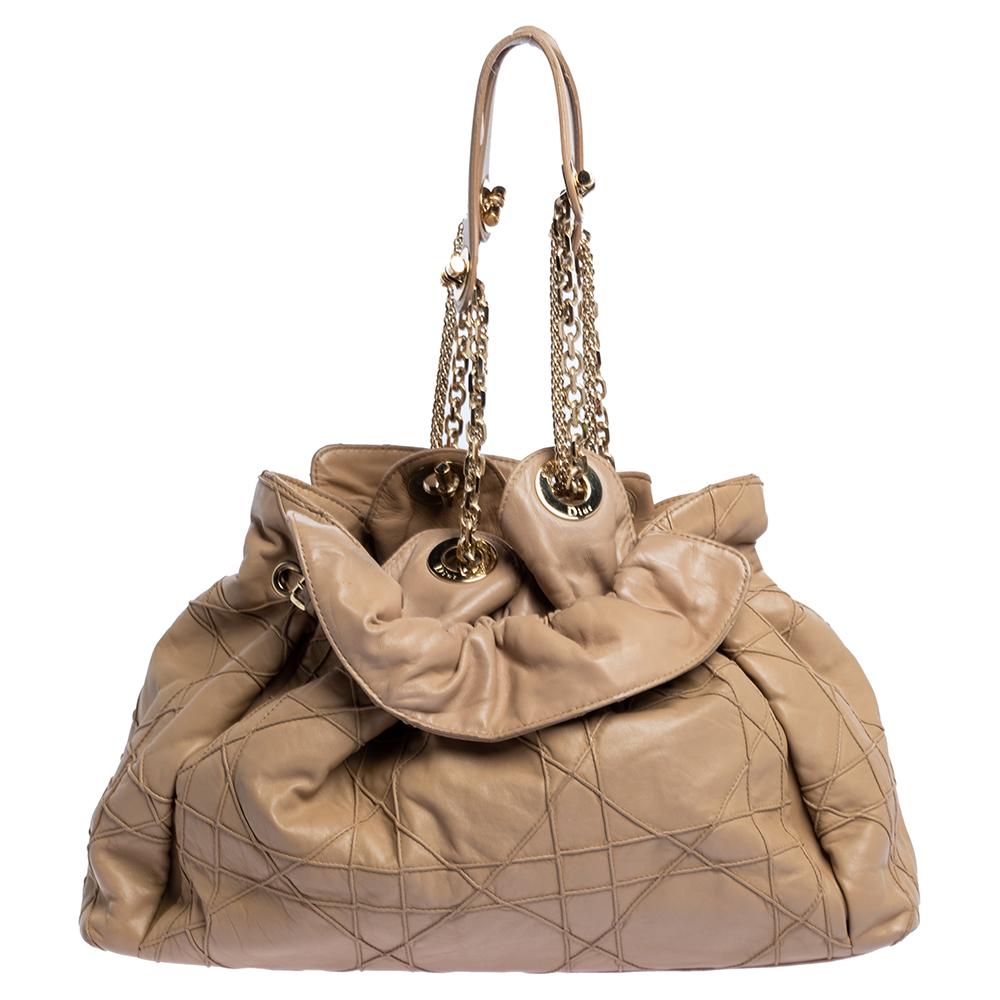 This stylish Le Trente hobo from Dior has been crafted from beige leather and styled with its signature cannage pattern. The bag features dual chain straps with leather shoulder rest, a CD cutout charm in gold-tone metal, a drawstring closure and