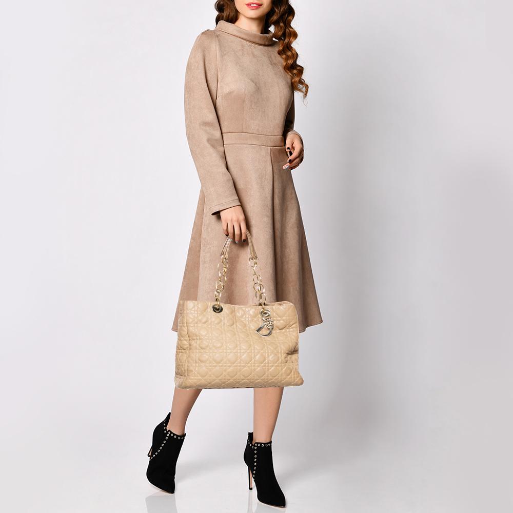 Impressive and high on style, this Lady Dior shopper tote from Dior comes made from beige leather and features the signature cannage quilted pattern on the exterior. It has dual top handles carrying attached 'DIOR' letter charms and a nylon-lined