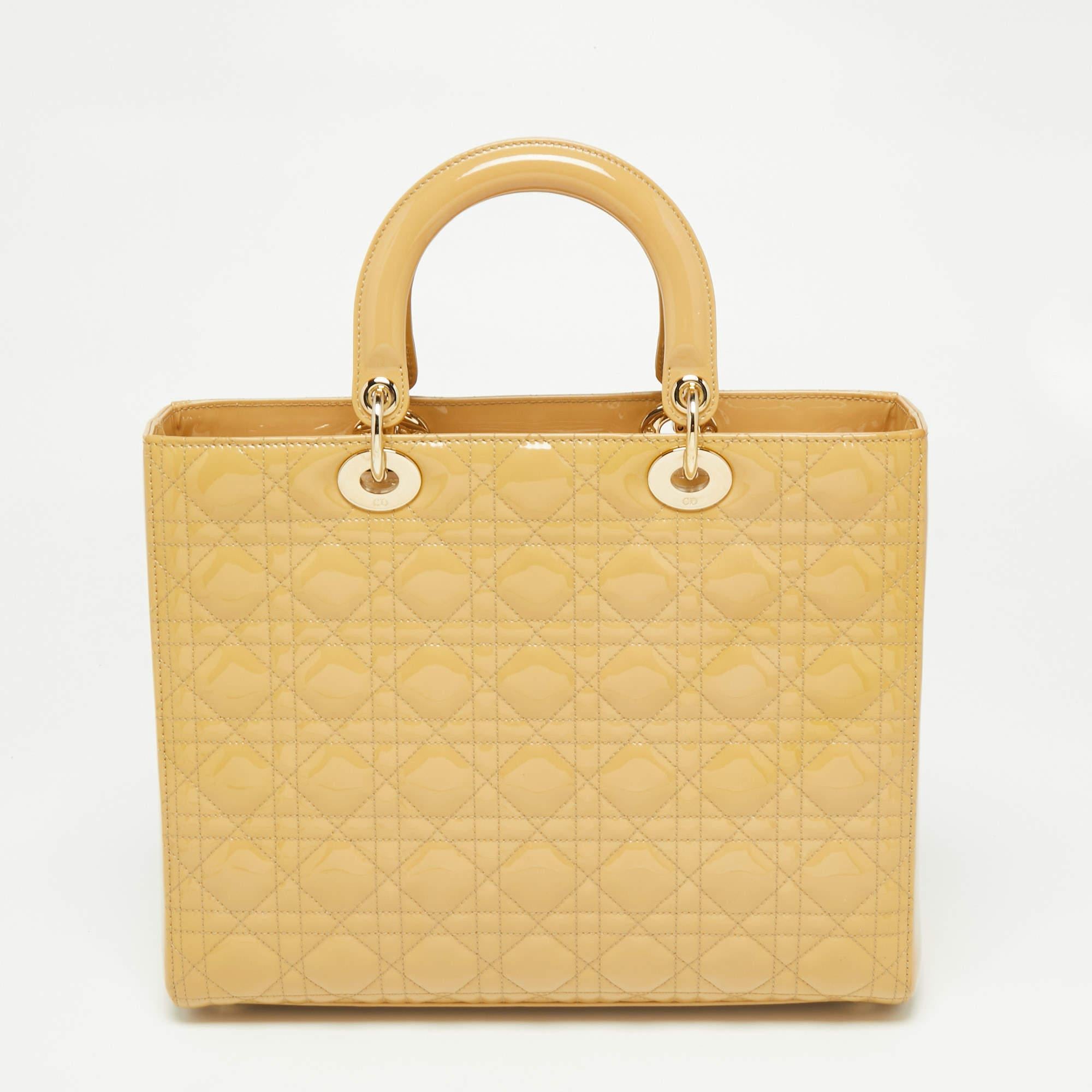 The Lady Dior tote is a Dior creation that has gained wide recognition and is a coveted bag that every fashionista craves to possess. The beige tote has been crafted from patent leather and carries the signature Cannage quilt. It is equipped with a