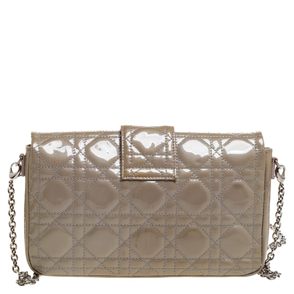 This stunning Miss Dior Promenade clutch is a compact version of the Miss Dior bag. Dazzling in a subtle beige shade, the bag is crafted from patent leather and features the signature Cannage pattern on the exterior, a detachable chain-link strap