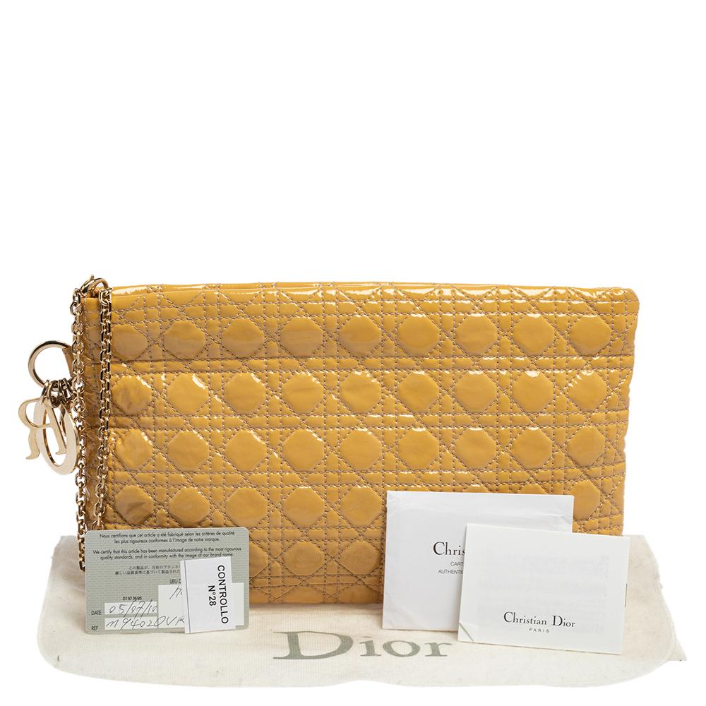 This Panarea clutch from Dior is a timeless piece. The bag comes in a luxurious patent leather cannage exterior with gold-tone hardware and Dior letter charms. It features double top handles and protective metal feet at the bottom. The nylon lined