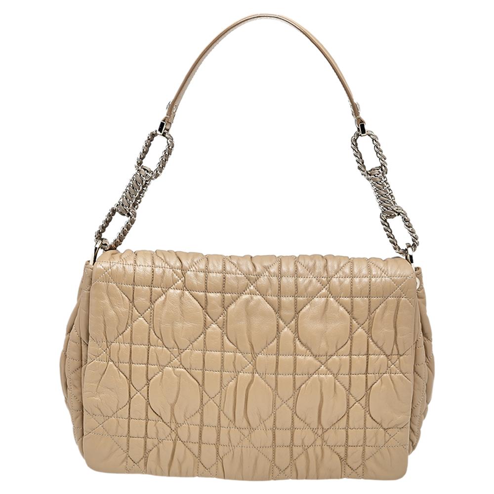This Delices bag from the House of Dior stands as a true testament to the label's longstanding prowess and aesthetic. This bag is created skillfully using beige Cannage quilted leather on the exterior and flaunts a sturdy structure, a single handle,
