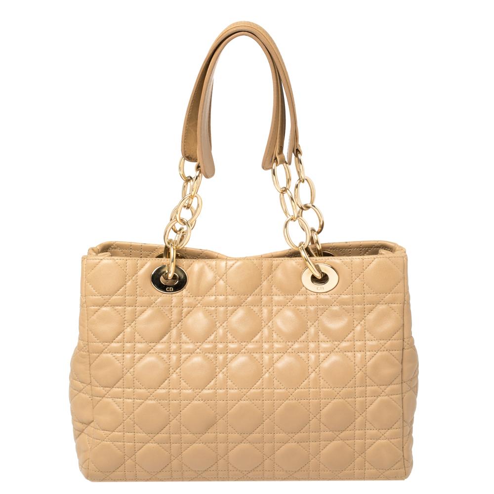 This shopping tote from Dior is a timeless piece. The bag comes with the signature cannage quilted exterior made from soft leather and accented with gold-tone hardware and Dior letter charms. It features dual handles and protective studs at the