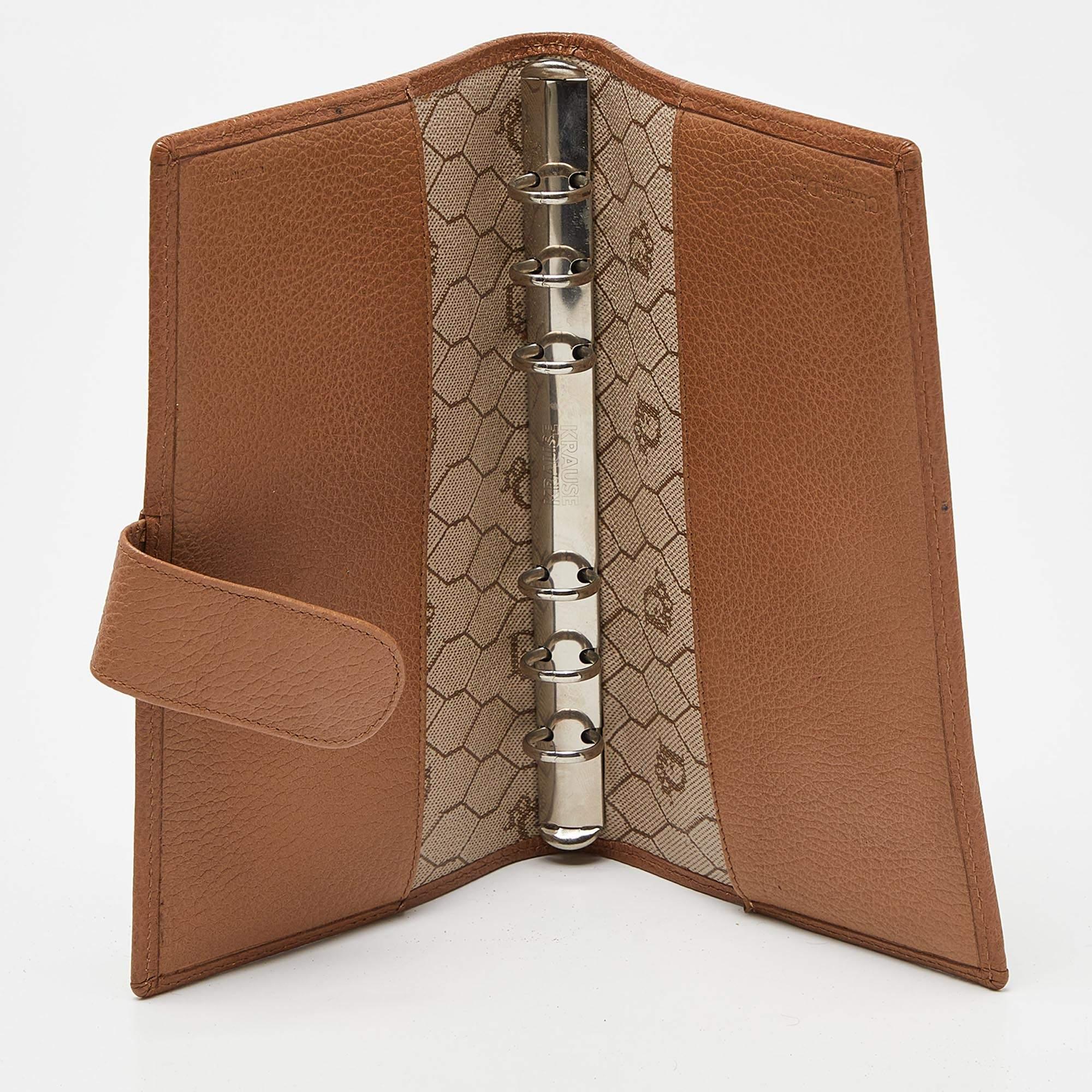 This designer agenda cover is made from coated canvas along with leather and we cant help but admire its fine finish and simple design. It features gold tone metal accents.