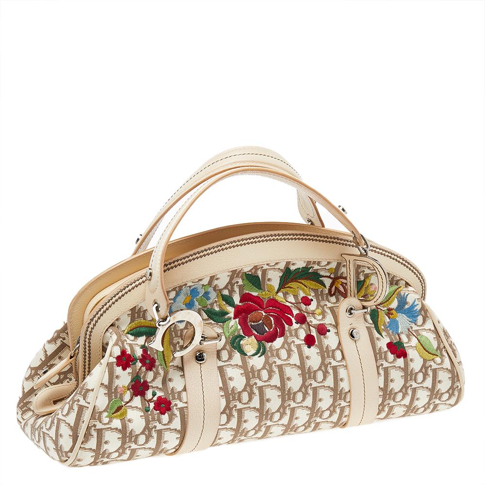 Head to your next social event carrying this chic Trotter bag from Dior. Designed in a Diorissimo-coated canvas body, this bag is finished with leather trims, silver-tone hardware, and floral embroidery on the front. It comes fitted with two top