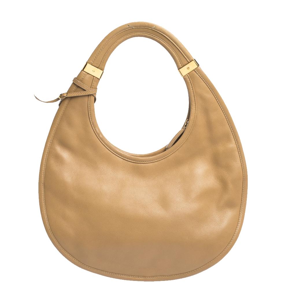 This Dior Diorita hobo is definitely a collector's piece! It features a smooth beige leather exterior and a Dior charm on the front. This hobo is lined with canvas and features a single zip pocket. Add a statement to your outfit with this bag on