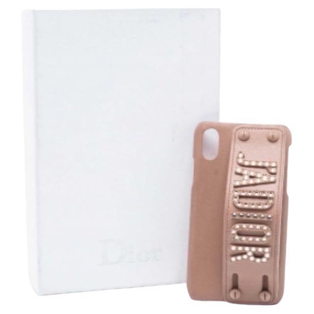 Dress up your iPhone X/XS stylishly while securing it with this cover from the House of Dior. Studded heavily with beautiful embellishments, this J'Adior cover is carved out of beige leather and lined with suede on the interior. This precious Dior