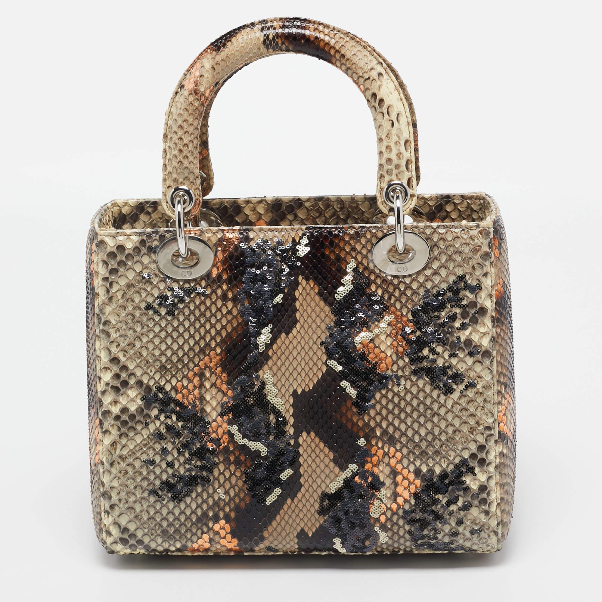 Die Dior Lady Dior Tasche ist eine exquisite Mischung aus Luxus und Kunstfertigkeit. Diese mittelgroße Tasche besteht aus einem raffinierten beigen Grundmaterial, das mit mehrfarbigem Pythonleder und aufwendigen Paillettenverzierungen verziert ist