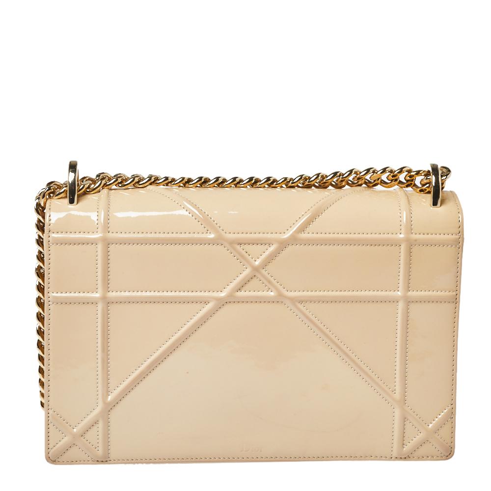 This Diorama bag is simply breathtaking! From its structured shape to its artistic craftsmanship, the bag sweeps us off our feet. It has been crafted from beige-hued patent leather and covered in the brand's signature Cannage pattern. A magnetic