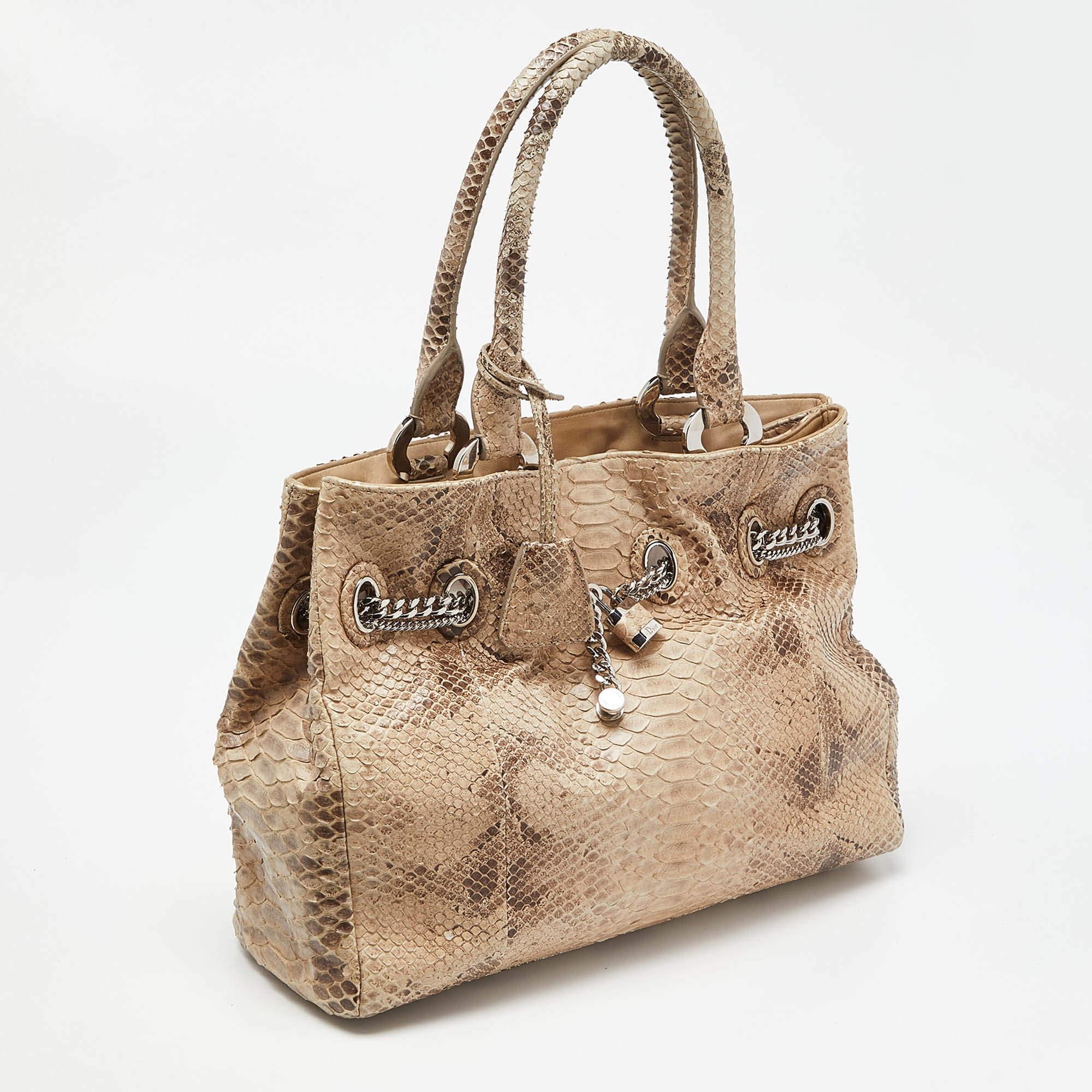 A lovely Christian Dior tote that has been crafted from leather and covered in the brand's signature Cannage quilt. It has two handles and a gold-tone chain drawstring that ends with a padlock on the front. The fabric interior is spacious and sized