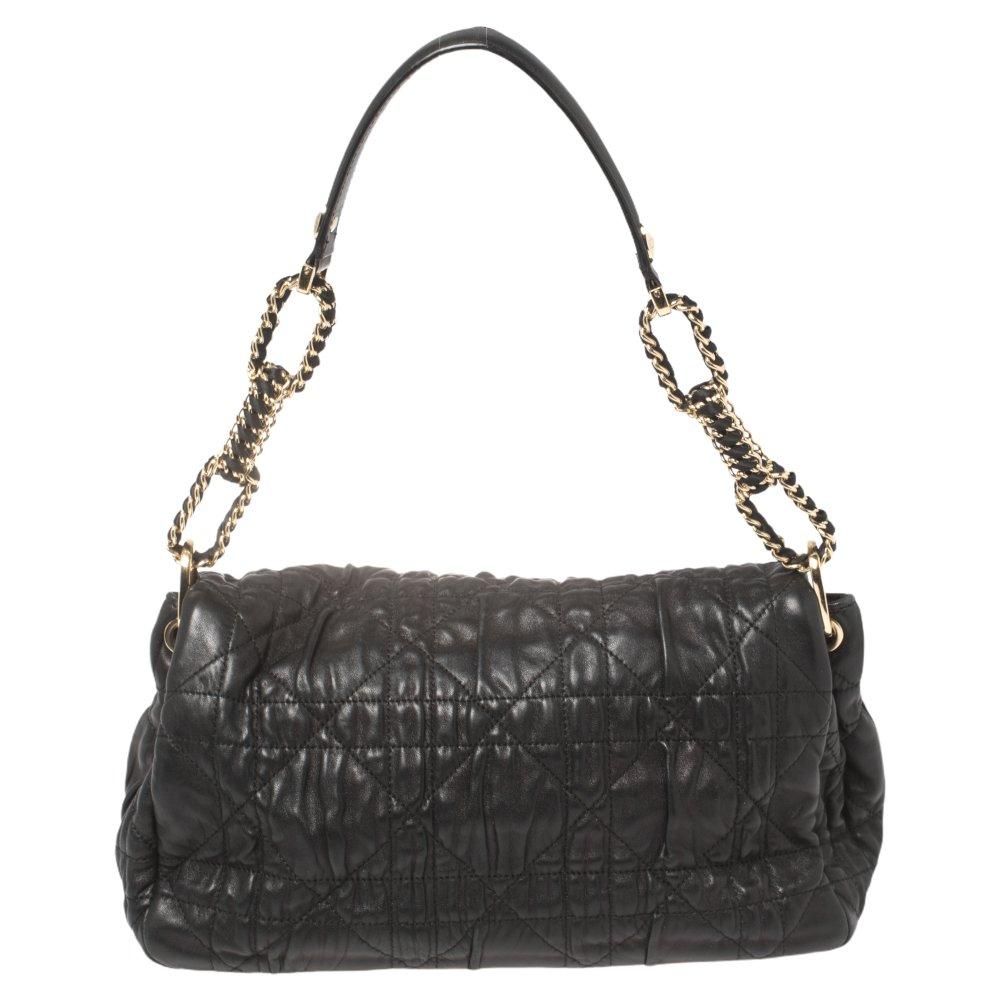 Seien Sie in dieser Saison der Trendsetter:: indem Sie diese edle schwarze Ledertasche von Dior schmücken. Das Innere der Tasche hat ein feines Stofffutter mit separaten Fächern für Ihre Essentials. Mit einem Klappverschluss hat die Tasche
