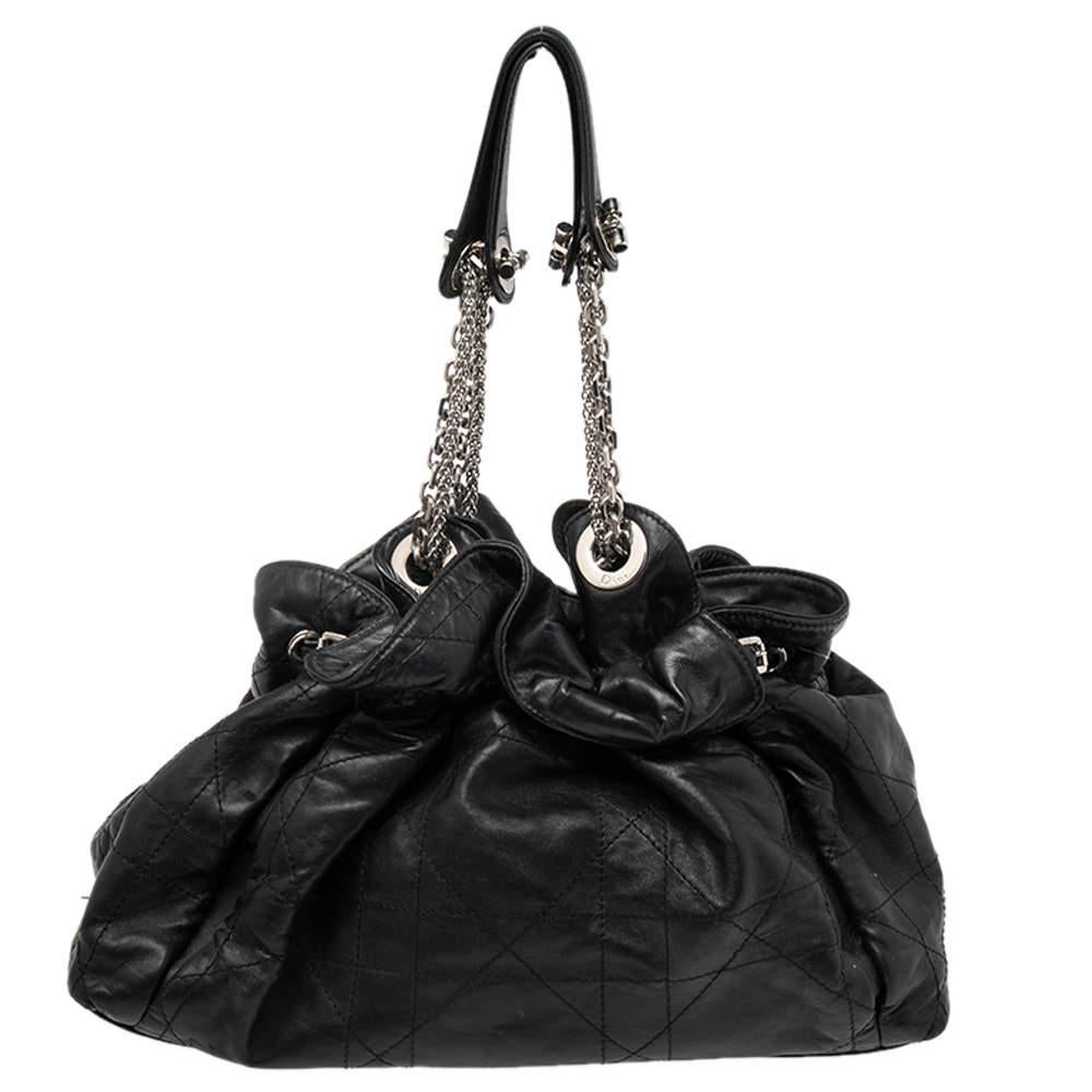 This stylish Le Trente hobo from Dior has been crafted from black leather and styled with the signature Cannage pattern. The bag features dual chain and leather handles, a 'CD' cutout charm in silver-tone, a drawstring closure, and protective metal