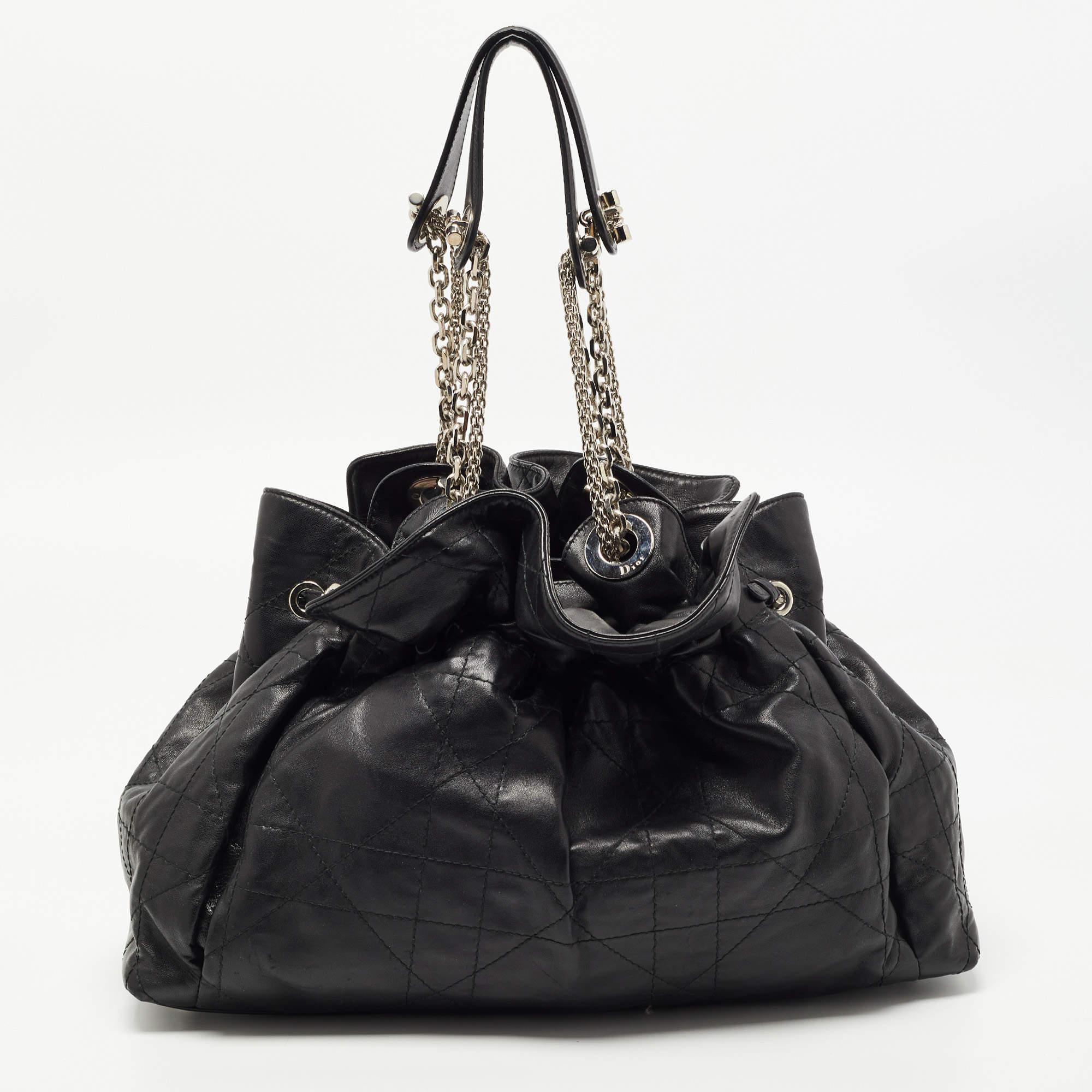 This stylish Le Trente hobo from Dior has been crafted from black leather. The bag features dual chain straps with leather shoulder rests, a CD cutout charm in silver-tone metal, a drawstring closure, and protective metal feet at the bottom. The