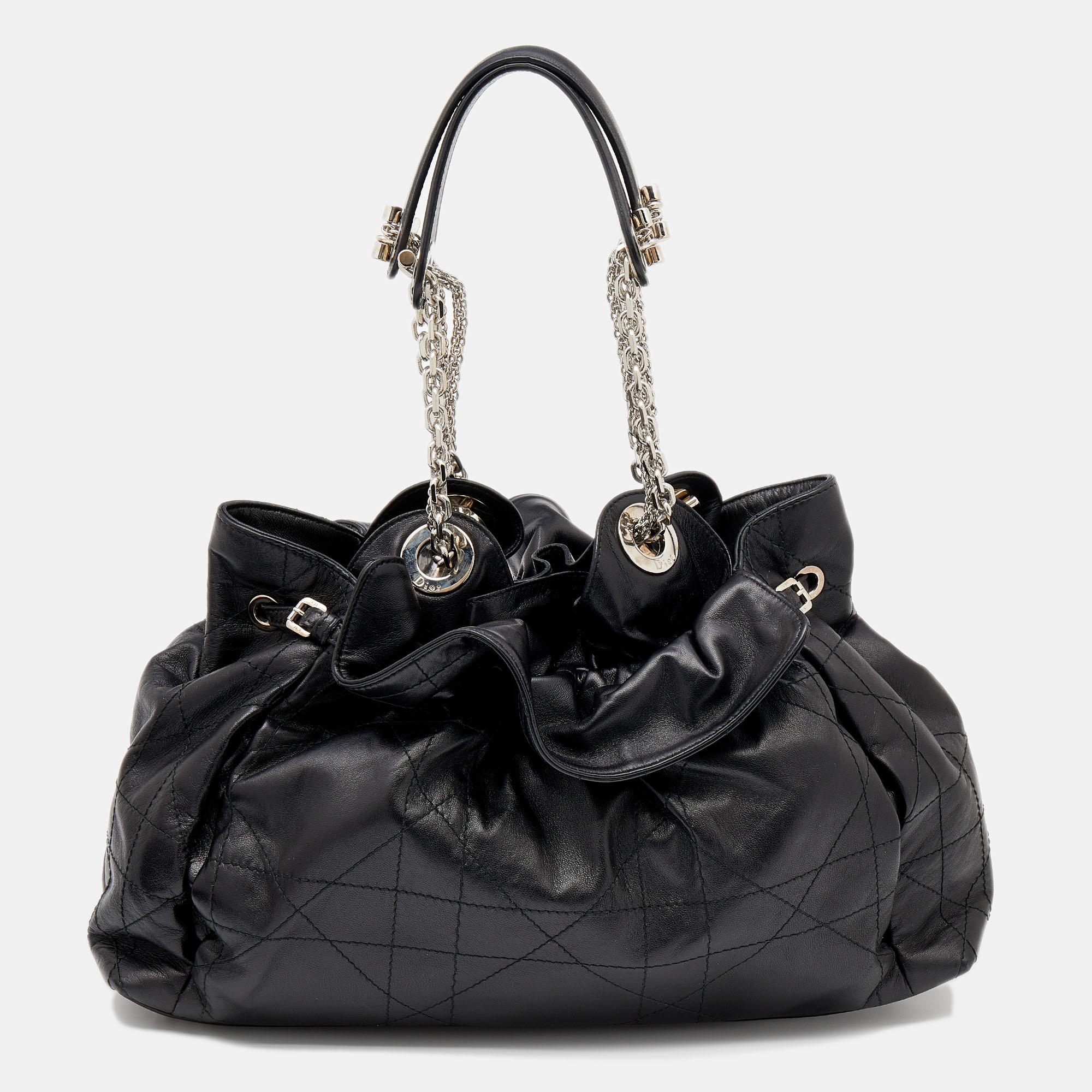 This stylish Le Trente hobo from Dior has been crafted from black leather and covered with the signature Cannage motif. The bag features dual chain-leather handles, a 'CD' cutout charm, a drawstring closure, and protective metal feet. The insides