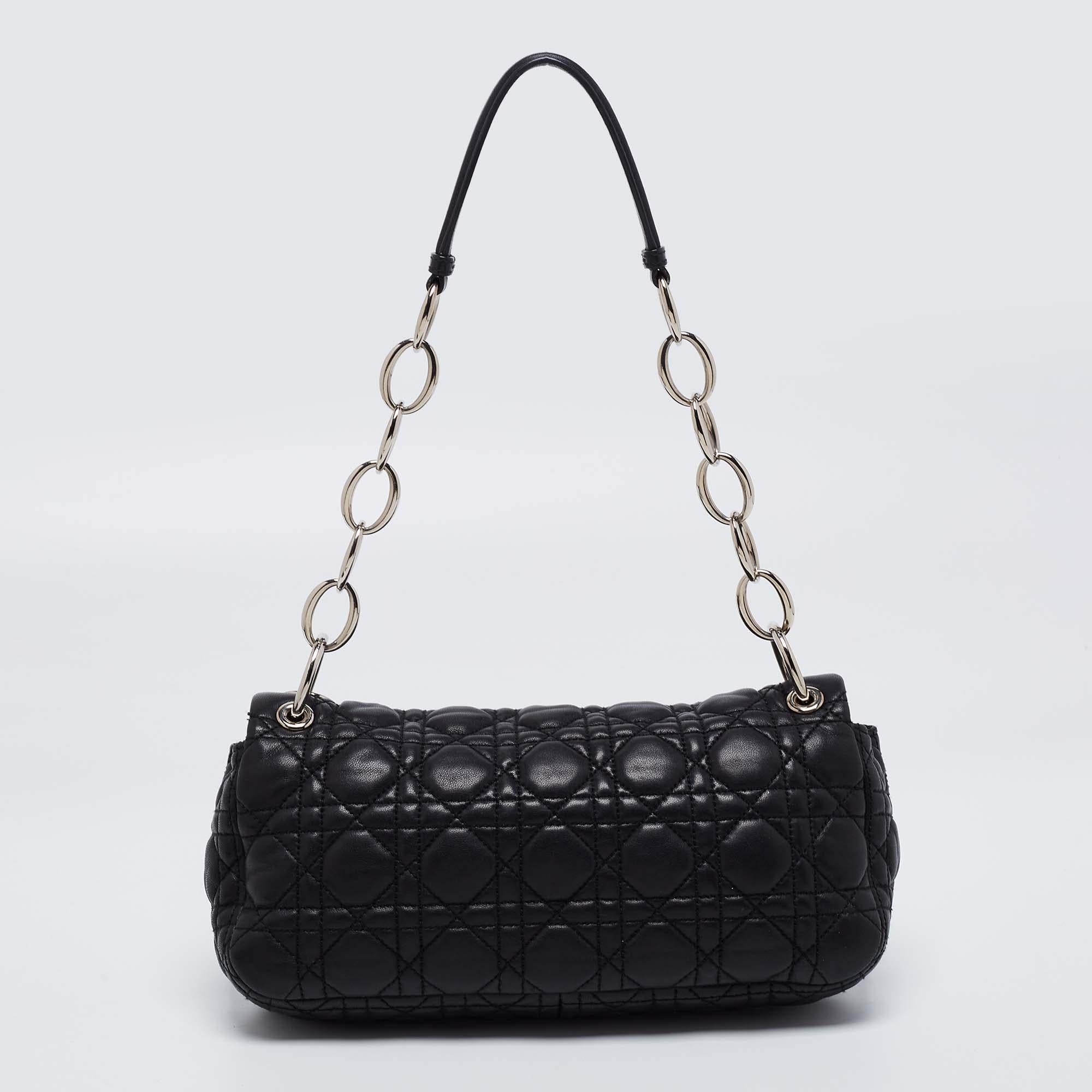 This black Rendezvous shoulder bag from Dior is chic and sophisticated. Crafted from black leather, it features a quilted design, chain-link strap with a leather shoulder pad, and dangling DIOR charms at the strap base. The iconic Dior closure opens