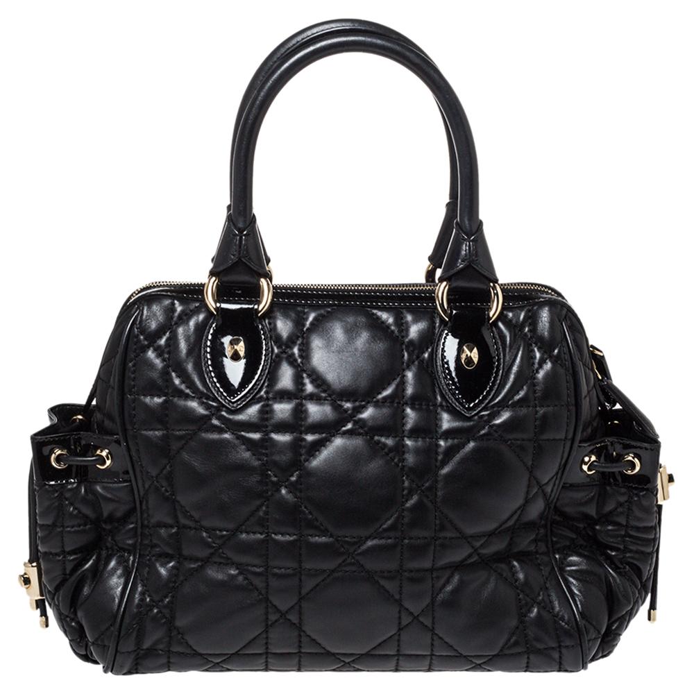This Dior satchel is a timeless handbag that you will love for years to come. This creation is made from Cannage-quilted leather with two side drawstring pockets. The sturdy rolled handles and top zip closure make this satchel ideal for everyday