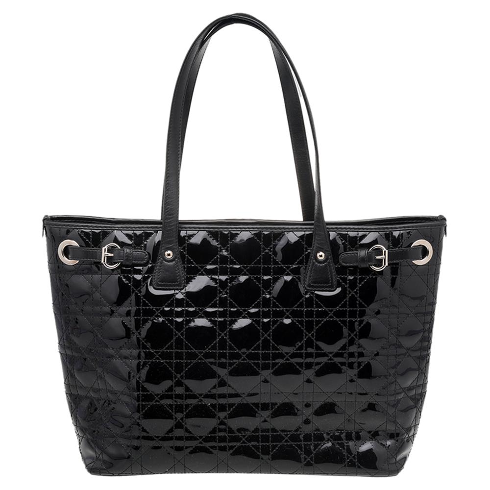This Panarea tote from Dior is a timeless piece. The bag comes in a luxurious patent leather Cannage exterior with silver-tone hardware and Dior letter charms. It features leather top handles and protective metal feet at the bottom. The nylon-lined