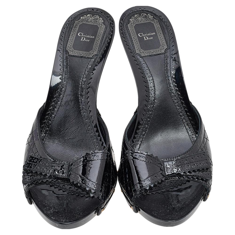 These clog sandals from Dior arrive in a comfortable design. Made in Italy, they feature Cannage patent leather uppers accented with a bow. The pair is complete with leather-lined insoles and a set of high heels. This is one pair that speaks