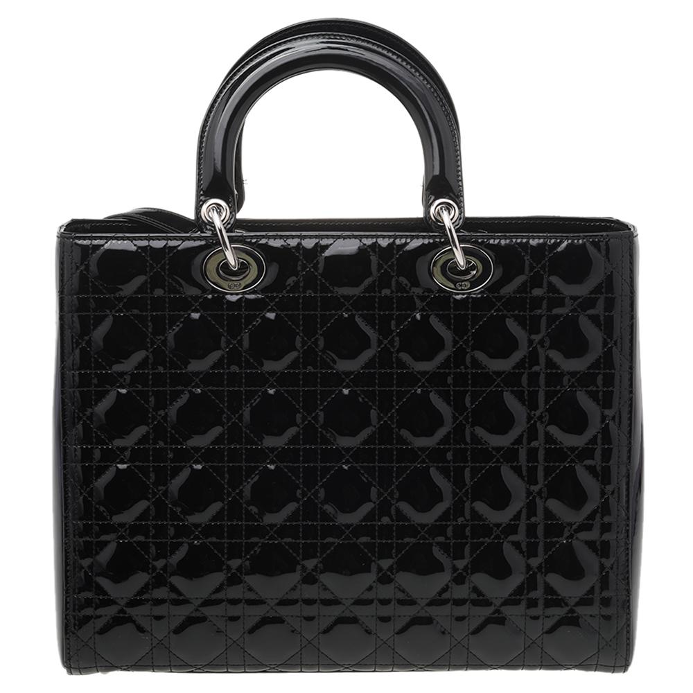 The origination of the Lady Dior tote by the House of Dior marks the commencement of a new trend and age in fashion. This Lady Dior tote has been created using black Cannage patent leather and flaunts a structured silhouette that is embellished with