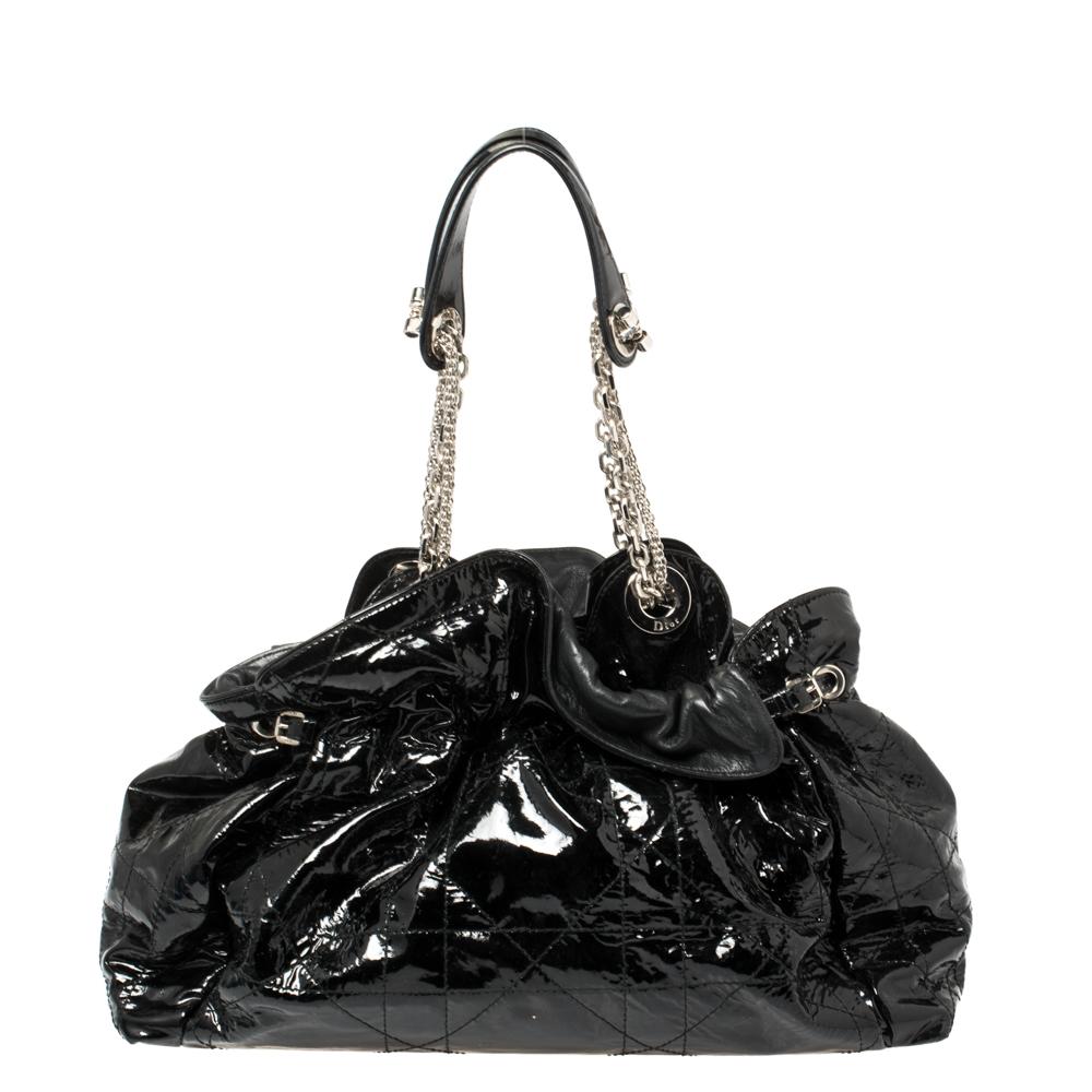 Le Trente hobo from the house of Dior is a unique bag for your everyday essentials. It is brilliantly designed in black patent leather with a Cannage pattern, ruffled top detail, and double shoulder strap. The drawstring top closure opens to reveal