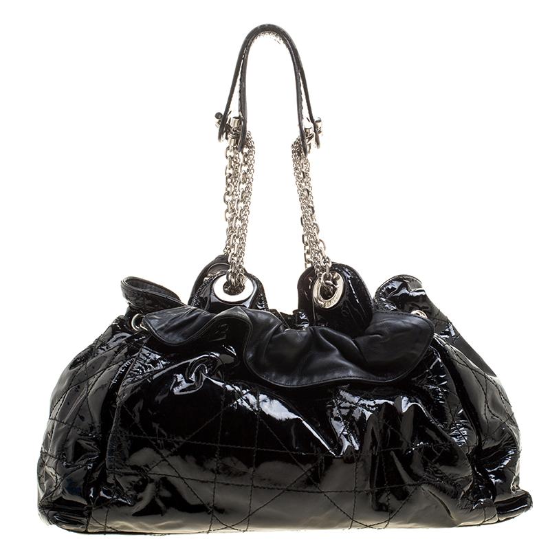 Le Trente' hobo from the house of Dior is a unique bag for your everyday essentials. It is brilliantly designed in black patent leather with a Cannage pattern, ruffled top detail, and double shoulder strap. The drawstring top closure opens to reveal
