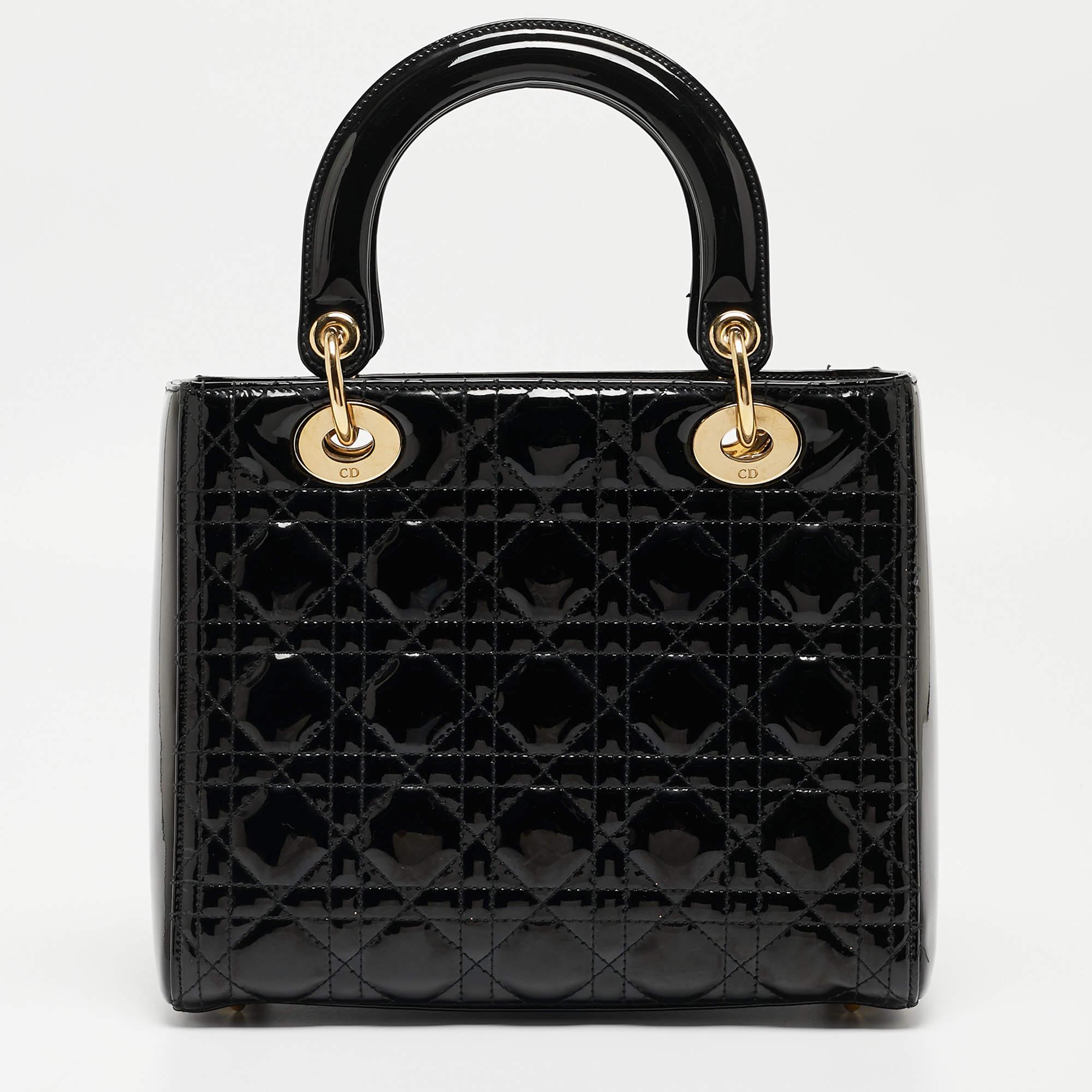 Ein zeitloser Status und ein großartiges Design kennzeichnen die Lady Dior-Tasche. Es ist eine ikonische Tasche, in die die Menschen bis heute investieren. Wir haben hier diese klassische Schönheit aus schwarzem Cannage-Lackleder. Die Tasche hat