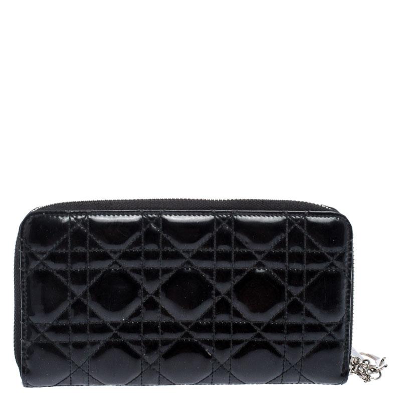 This Lady Dior wallet is conveniently designed for everyday use. Crafted from patent leather, the exterior has a quilted cannage pattern and a zipper with DIOR letter charms on the zipper pull. The leather lined interior houses multiple card slots,