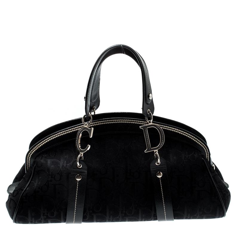 Restez élégante avec cet adorable sac de Dior. Il est confectionné en toile enduite signée Diorissimo et doté de finitions en cuir. Cette sacoche est ornée d'une broderie florale sur le devant, de ferrures argentées et de courtes poignées en cuir