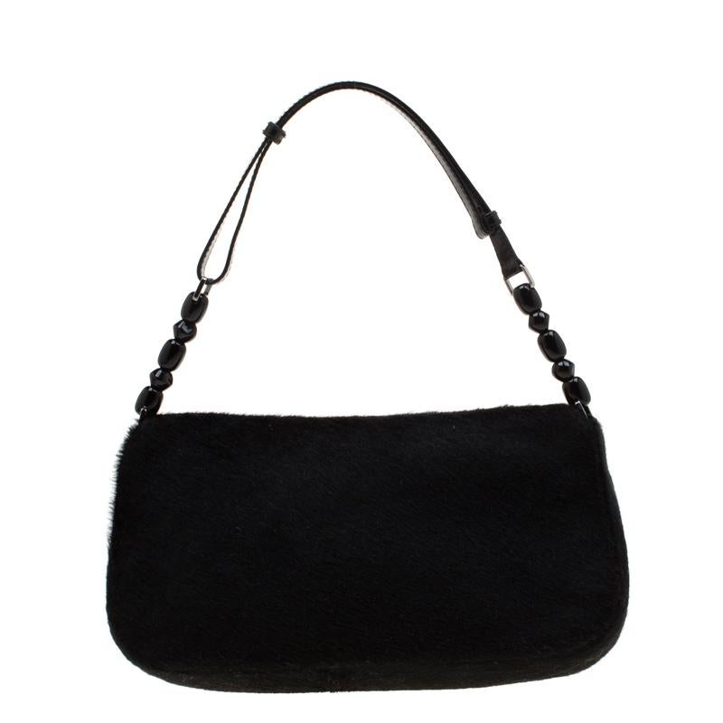 Go back in time with the vintage design of this Christian Dior Maris Pearl bag. Featuring a black embellished exterior, the calf hair body gives an exotic touch. Combined with the silver-tone hardware, it has a single shoulder strap. The magnetic