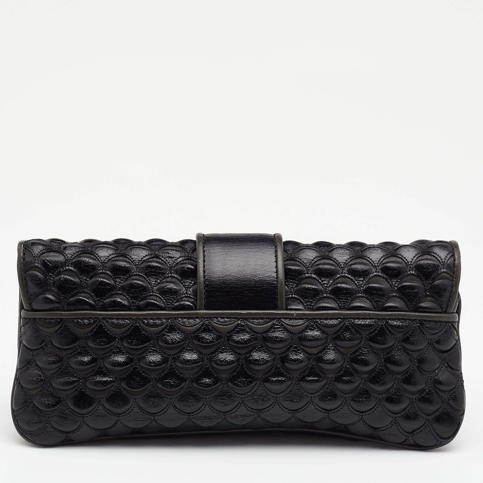 This unique clutch by Dior is crafted from fish scale leather in a black and grey hue. It features a textured exterior and a front flap. It opens to a satin-lined interior well-sized to hold your daily essentials.

Includes: Mirror