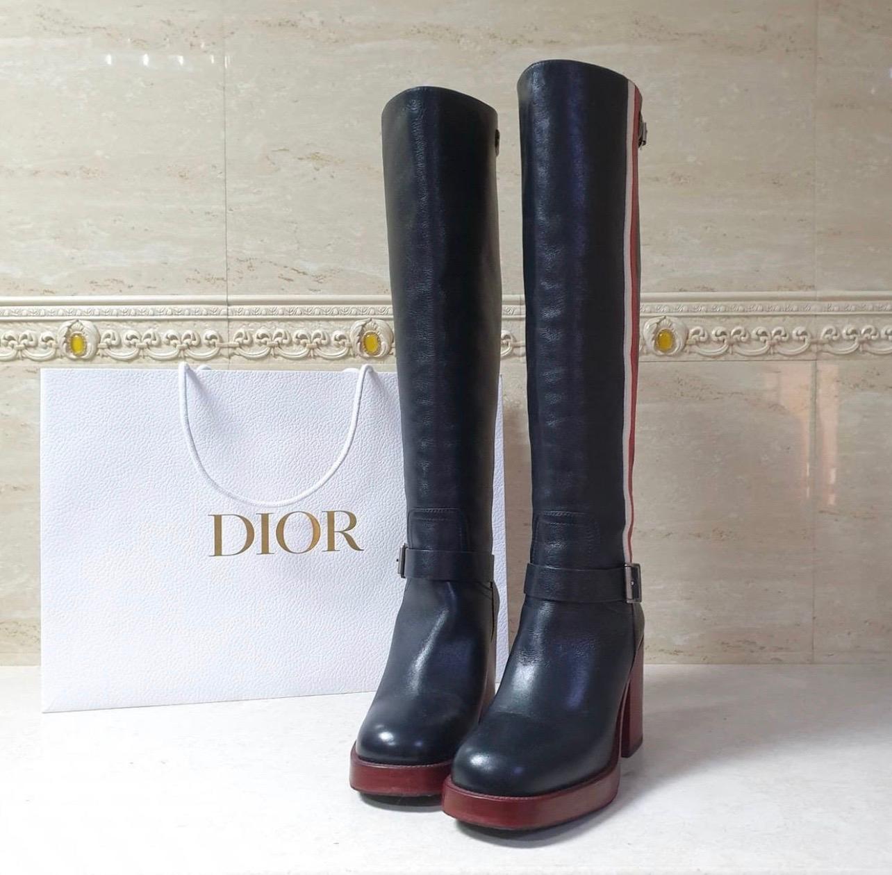 Black leather Christian Dior tall pull-on boots that features red and white leather racing stripe accent, silver tone buckle fastening, round toe, red stacked block heel and rubber protective sole. 
Sz.37.5
Very good condition
No original packaging.
