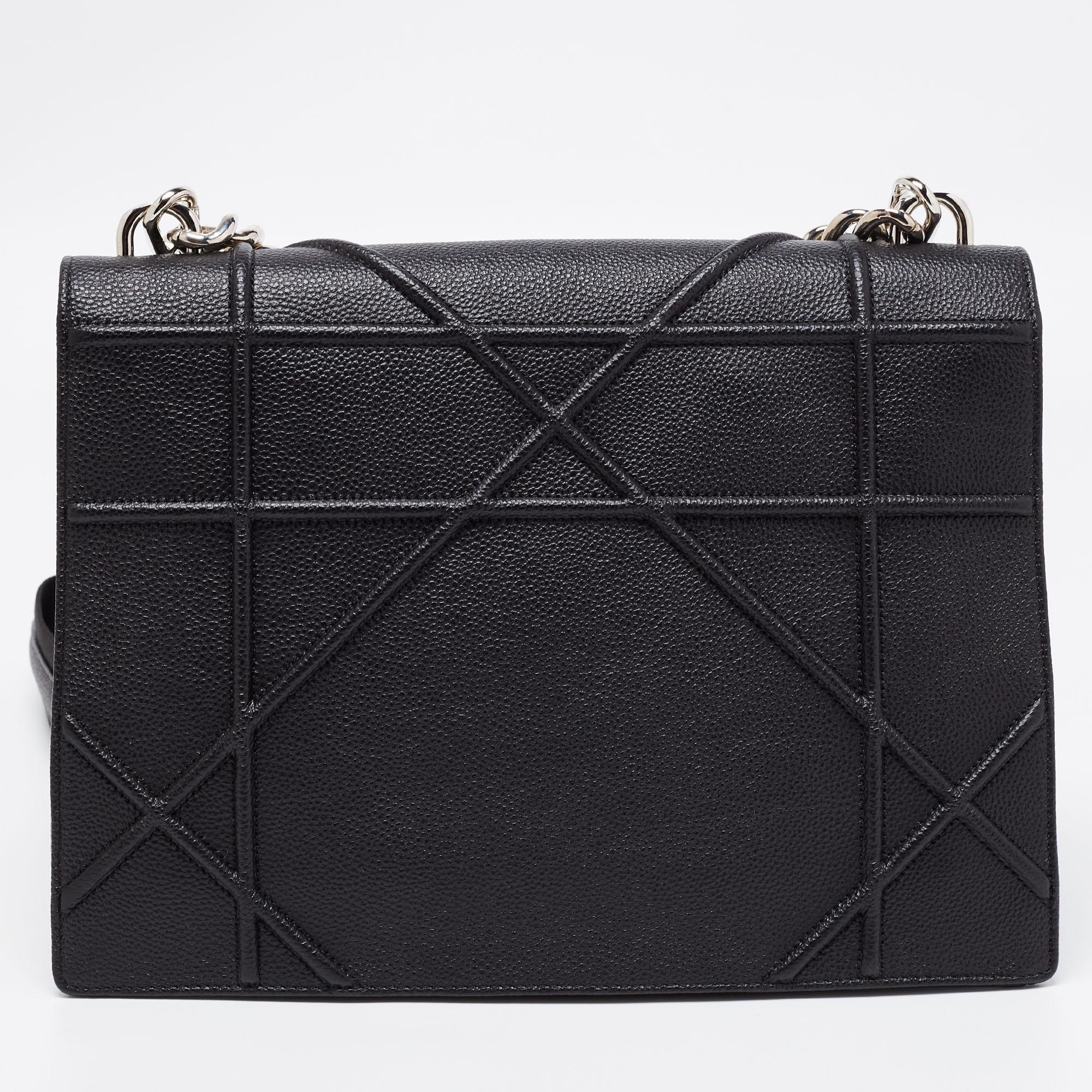 This Diorama bag has been crafted from black leather into a compact design. Magnetic closure on the flap secures a fabric interior, and a shoulder strap, as well as a short chain, is provided for you to carry it. You will surely love parading this