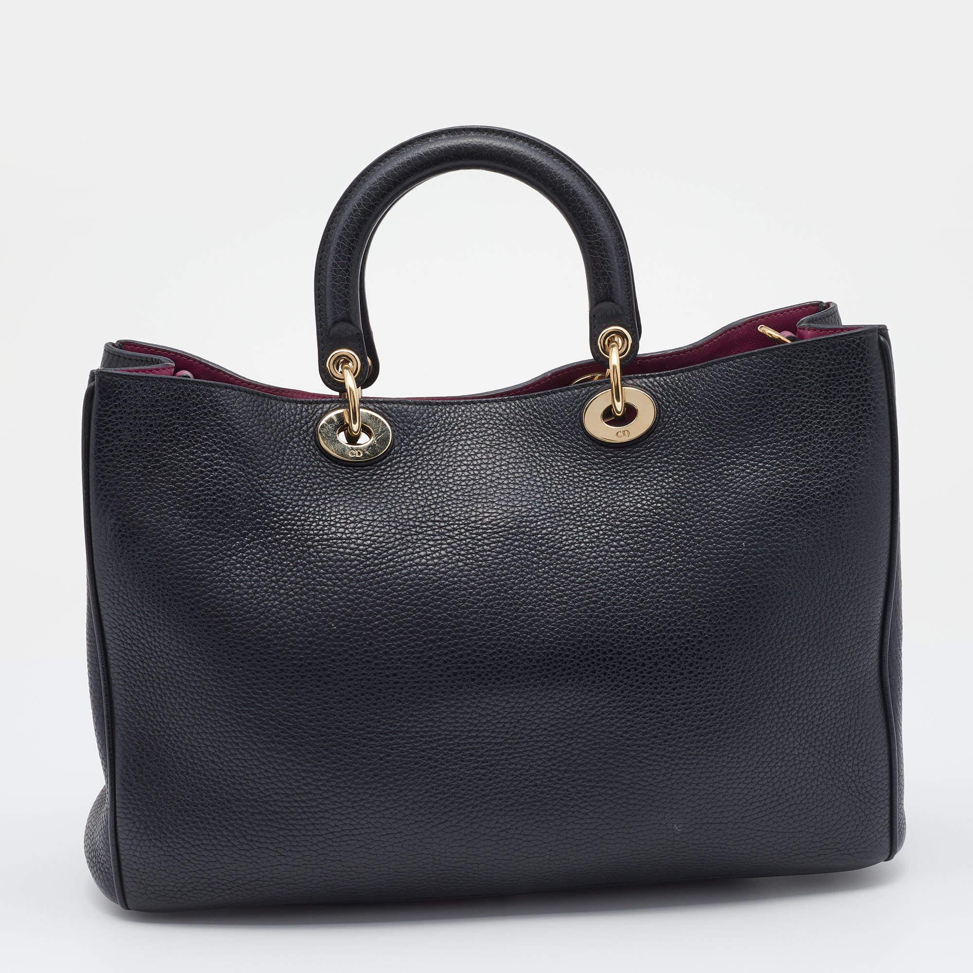 Ce sac Diorissimo Shopper de la Maison Dior vous permettra de ranger vos affaires en toute sécurité et avec style. L'extérieur est en cuir et le devant est orné de charmes D.I.O.R. aux tons dorés. Il est doté de deux poignées, d'une bandoulière et