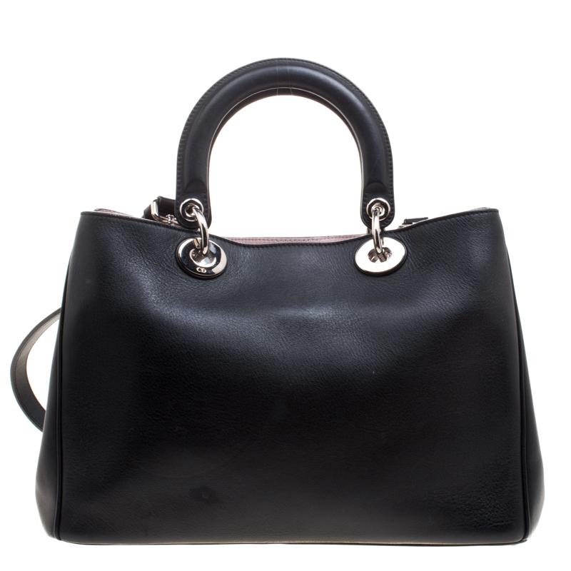 The Diorissimo bag from Dior is a timeless piece. The leather bag comes in a luxurious black color with silver-tone hardware and Dior letter charms. It features double top handles, a detachable shoulder strap and protective feet at the bottom. A