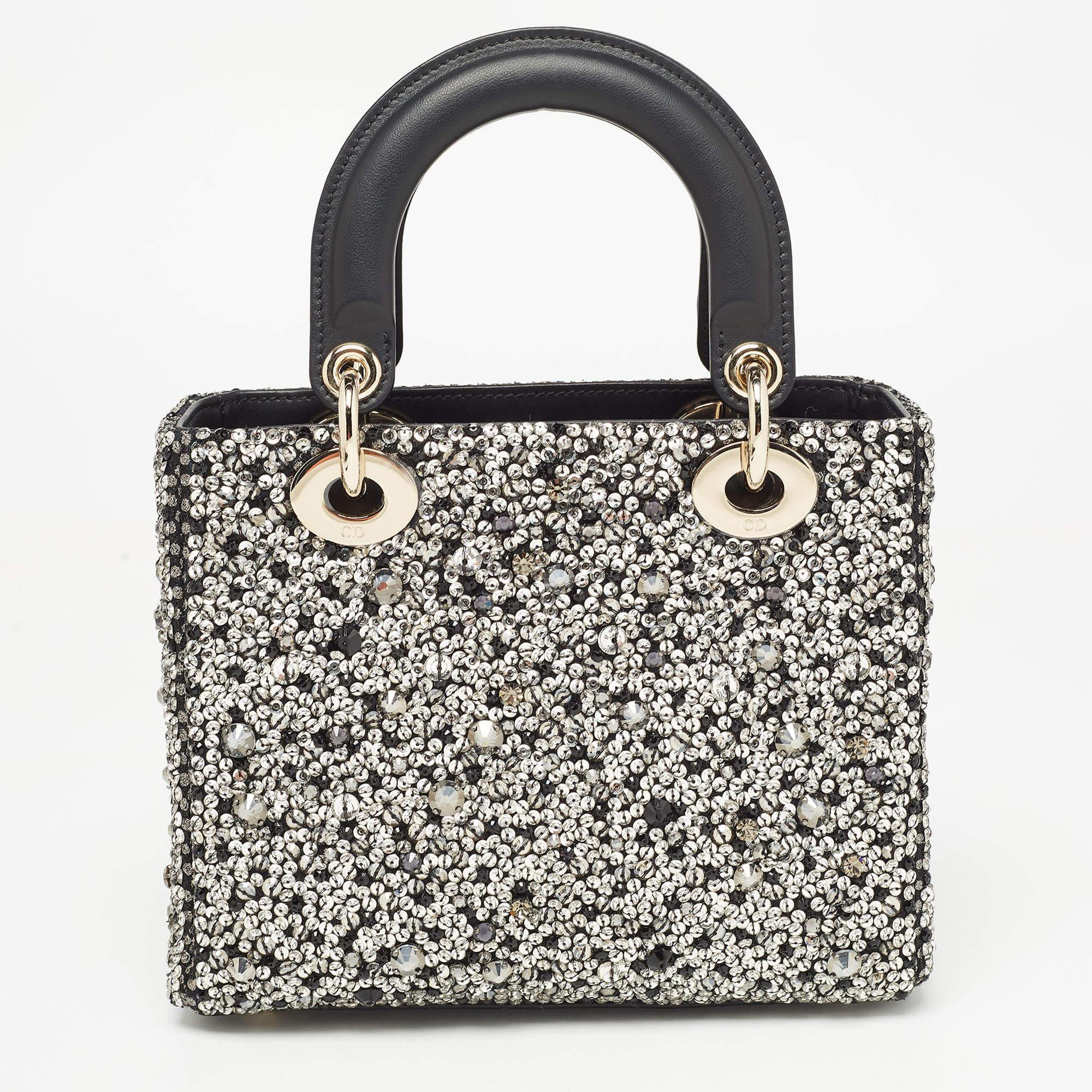 The Lady Dior Tote exudes timeless elegance. Crafted from luxurious black leather, it features intricate sequin and crystal embellishments, creating a dazzling yet sophisticated aesthetic. The small size adds a touch of refinement to any ensemble,