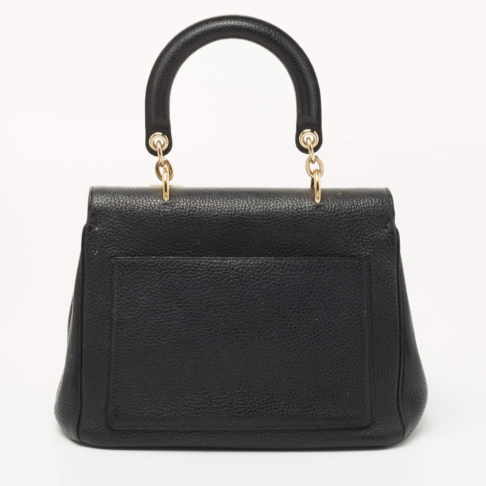 This Be Dior bag from the House of Dior is sure to add sparks of luxury to your wardrobe! It is crafted using black leather on the exterior, with the signature D.I.O.R charms embellishing the front. It has a top handle, gold-toned hardware, and an